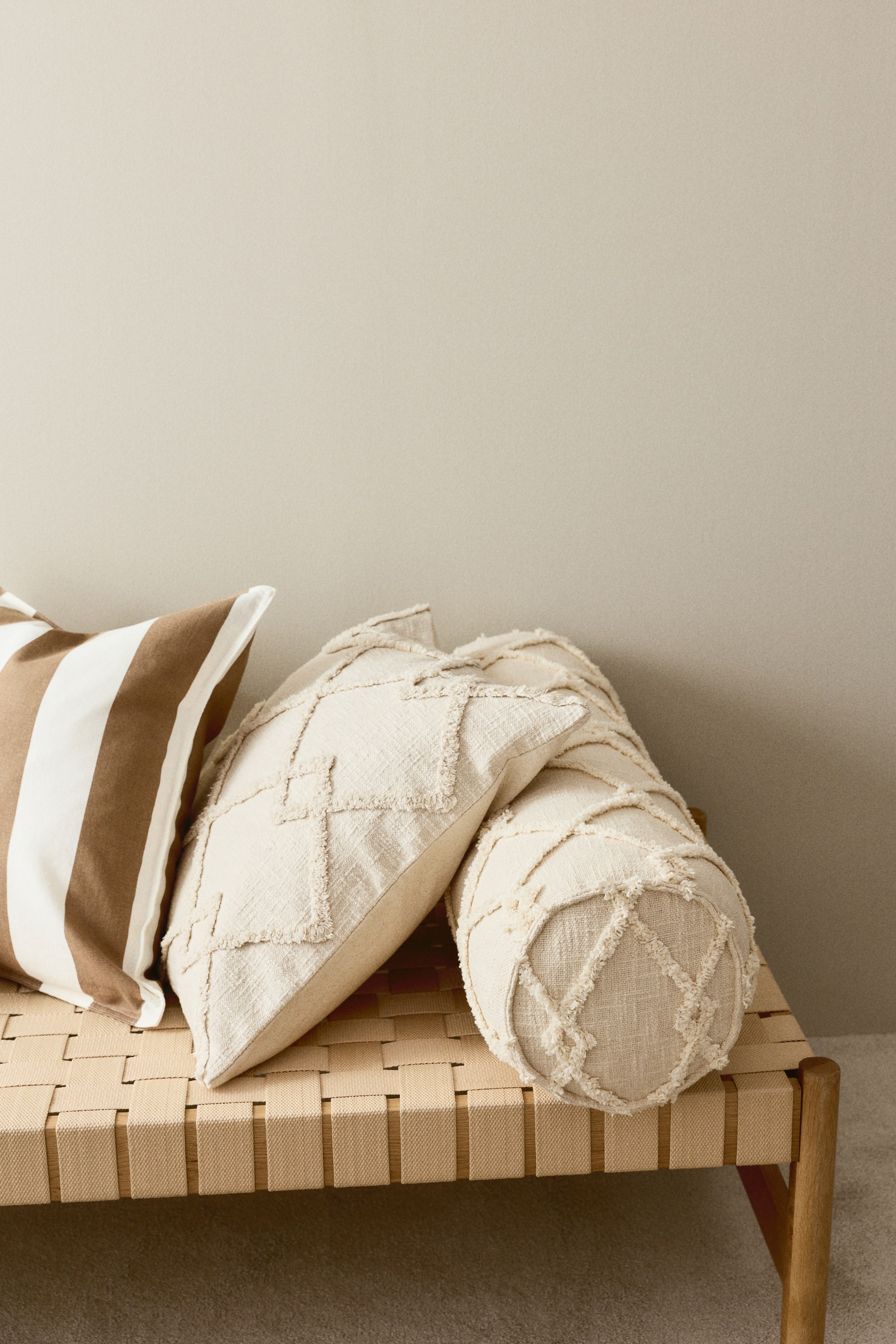 이미지 확대 보기: 볼스터는 원통형 모양 전체에 걸쳐 푹신한 기하학적 패턴이 돋보이는 약간의 질감이 있는 면직물을 선보입니다.