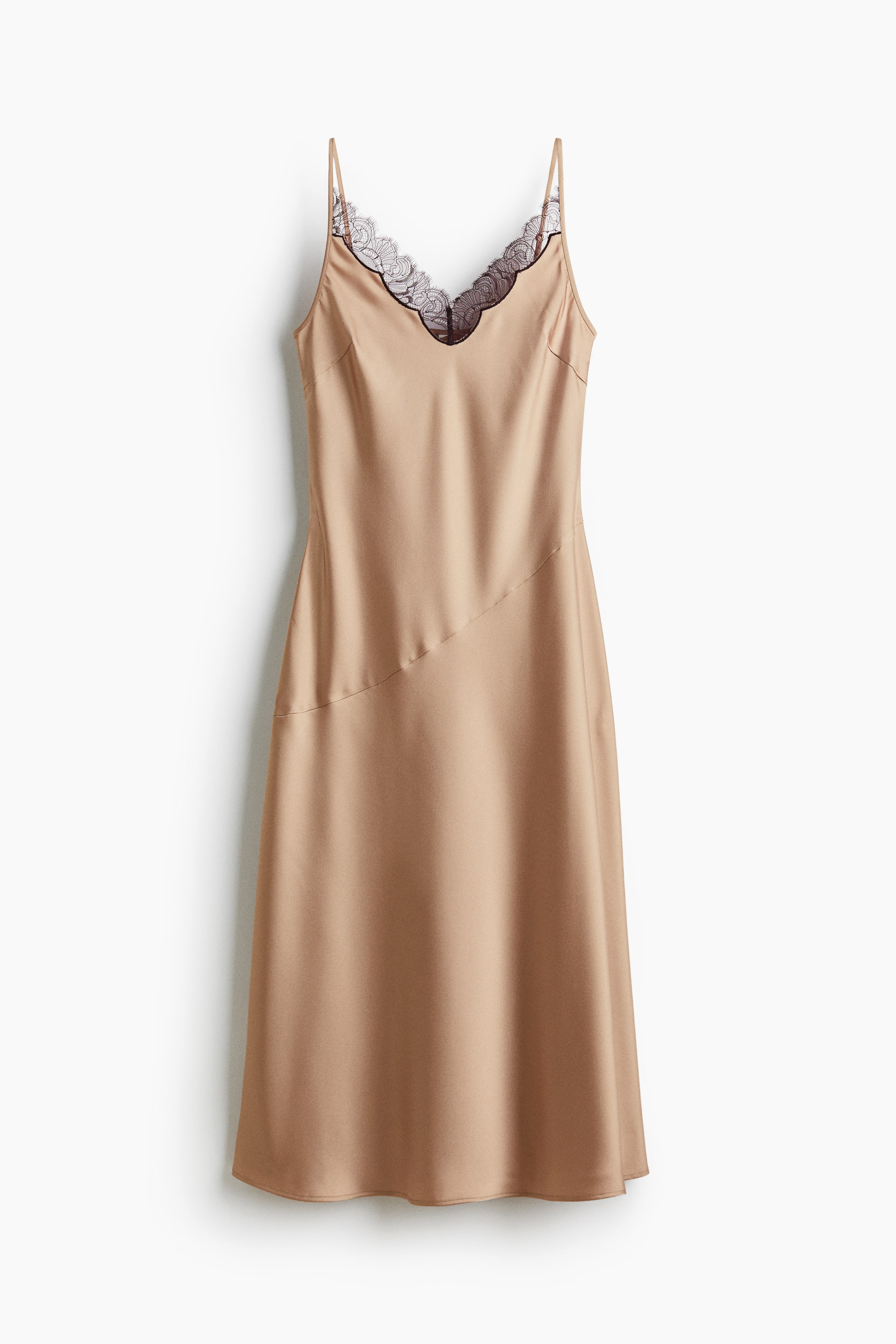 View larger image: A champagne-colored, satin-effect slip dress is featuring a V-neckline with black lace trim, thin spaghetti straps, and a prominent diagonal seam across its front.