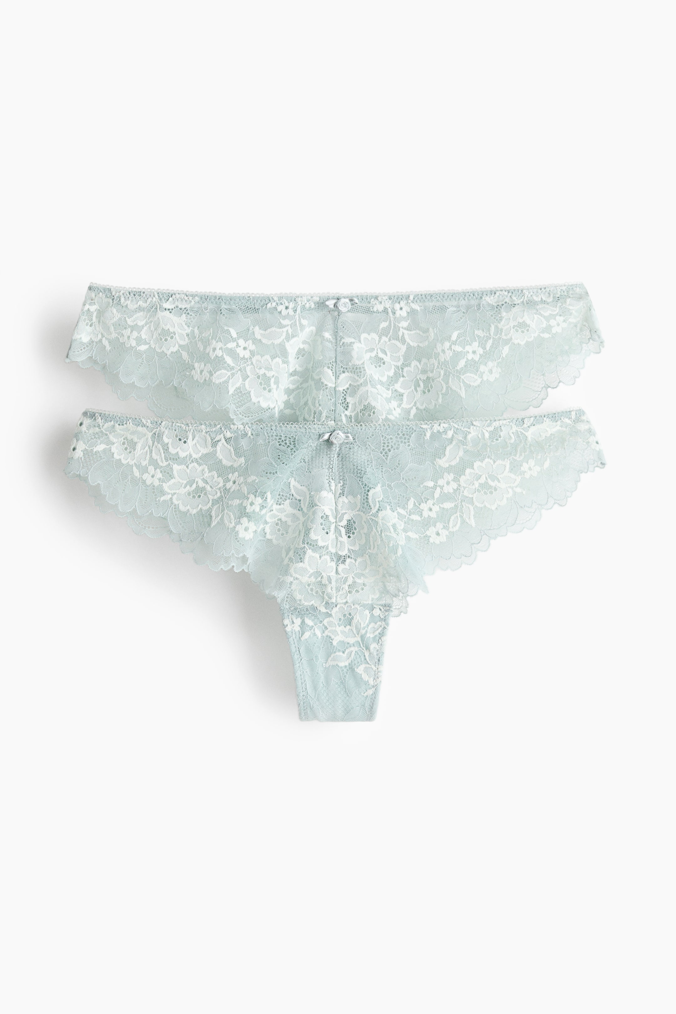 Grotere afbeelding bekijken: Twee strings worden gepresenteerd, de ene iets boven de andere geplaatst, beide naar voren gericht. Ze zijn gemaakt van lichtblauw kant met witte bloemenpatronen en geschulpte randen. Elke string toont ook een kleine witte strik aan de voorkant van de tailleband.