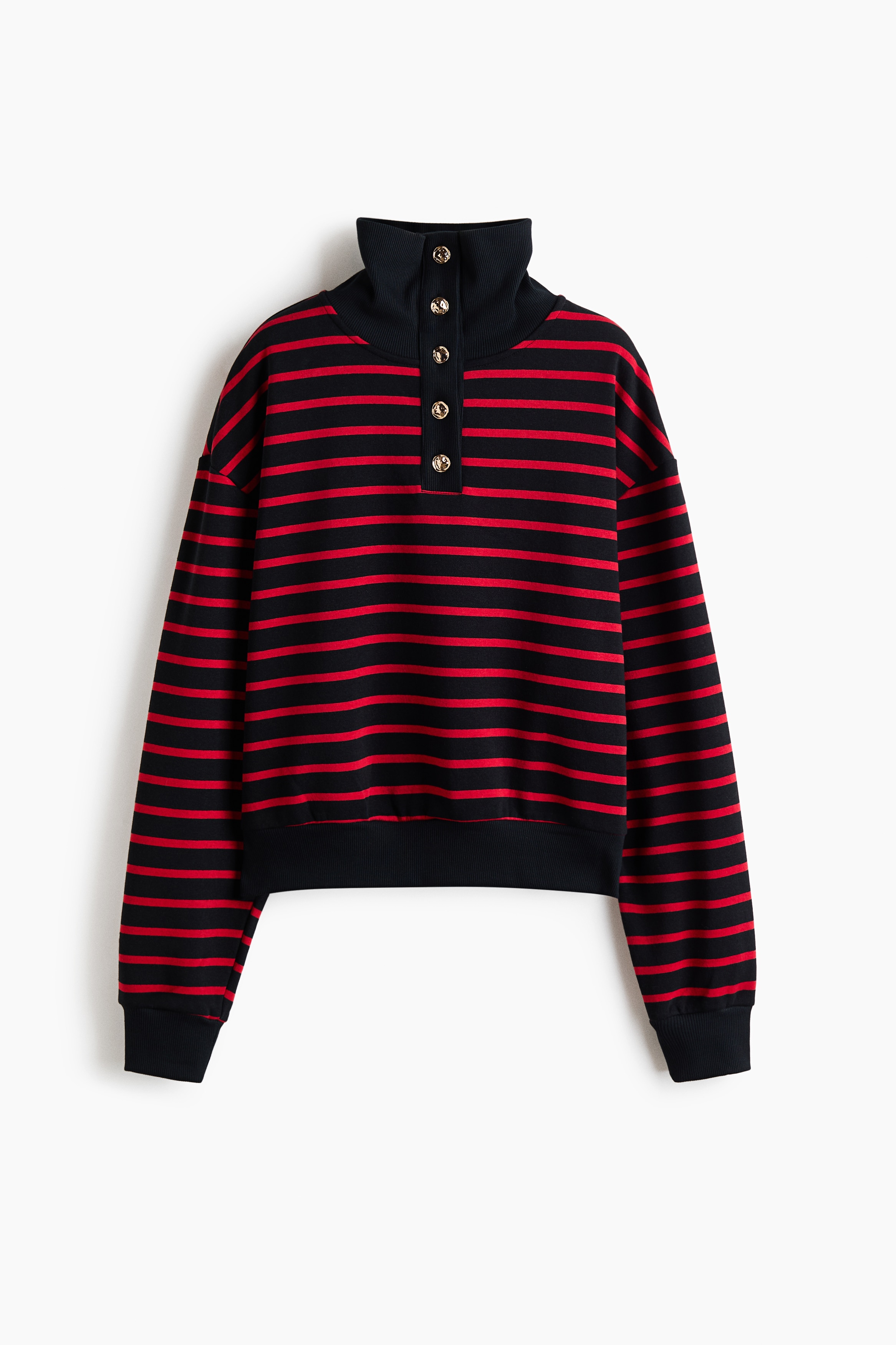 A relaxed-fit red and black striped sweater is worn by the model, featuring a black ribbed stand collar with a gold-button placket and dropped shoulders. The sweater is styled with light-wash blue jeans, and a textured yellow-and-brown patterned bag is carried over the shoulder.