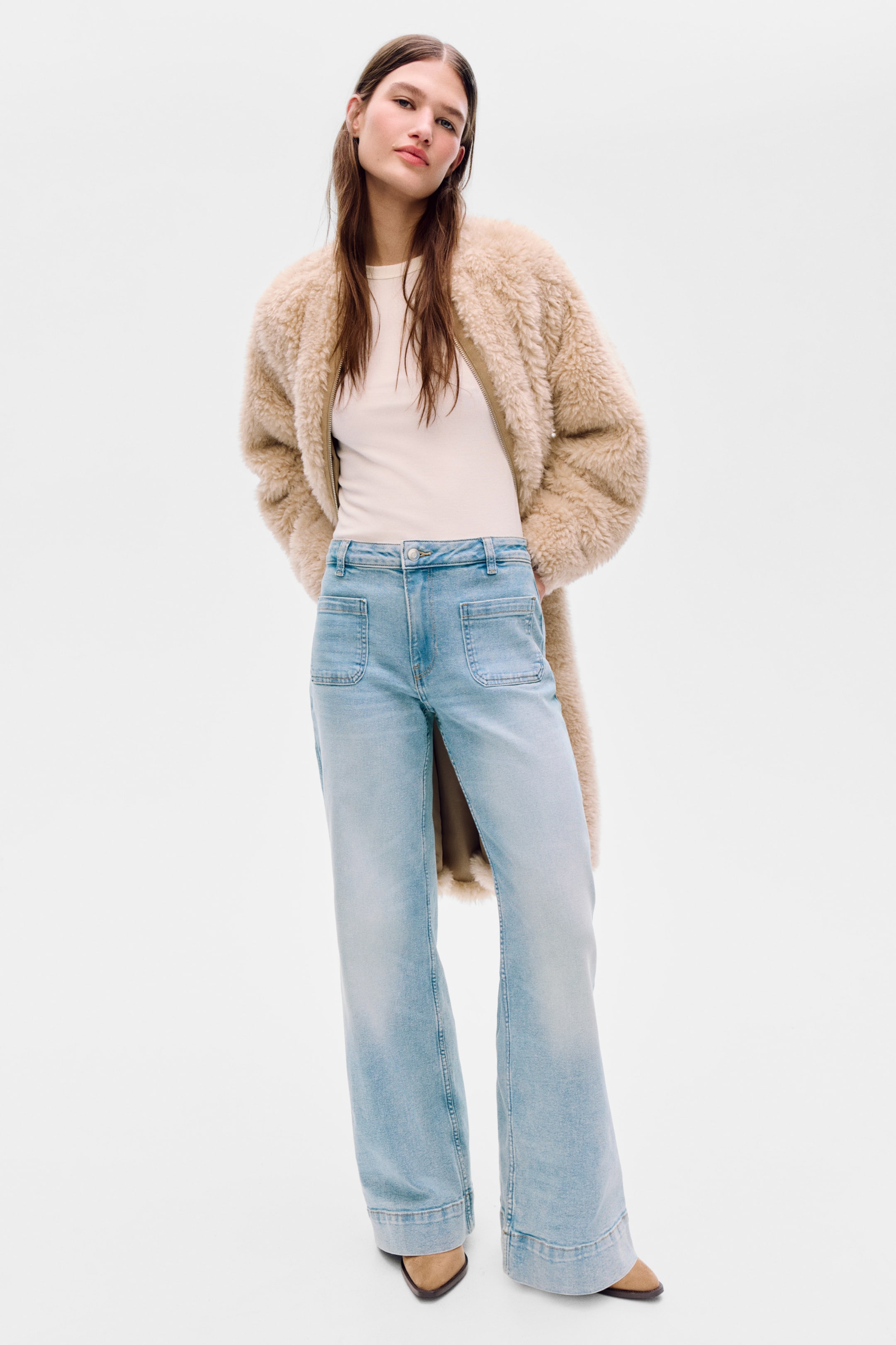 Visualizza immagine più grande: Jeans in denim azzurro chiaro con vita alta, chiusura con bottone e zip, tasche applicate sul davanti e taglio a gamba larga, aderente dalla vita fino ai fianchi. La modella indossa i jeans, che coprono la parte superiore di scarpe a punta.