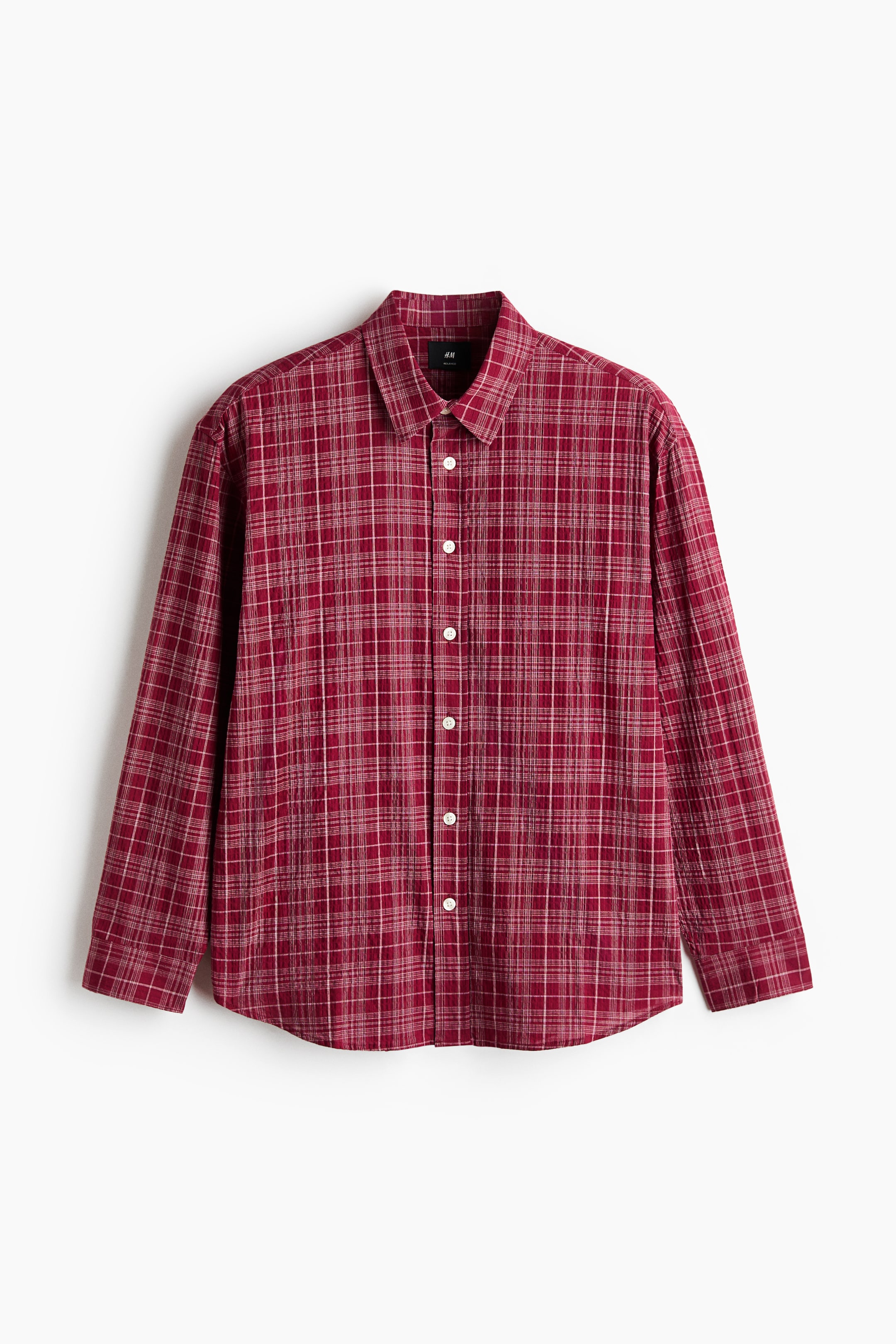 View larger image: A red checked shirt is facing directly forward, featuring a standard collar and a button-up front with white buttons. Thin white and light brown lines are forming the checked pattern.