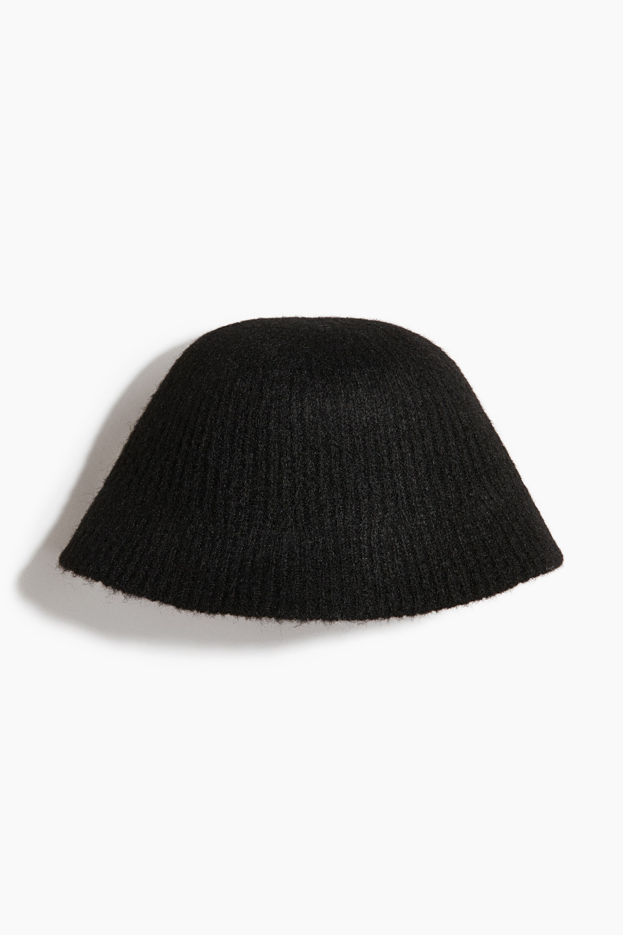 Agrandir l'image: Un bob en maille noire avec une finition texturée et duveteuse est présenté de face. Le chapeau affiche une calotte arrondie en forme de cloche, avec un bord incliné et une structure en maille côtelée fine sur l’ensemble.