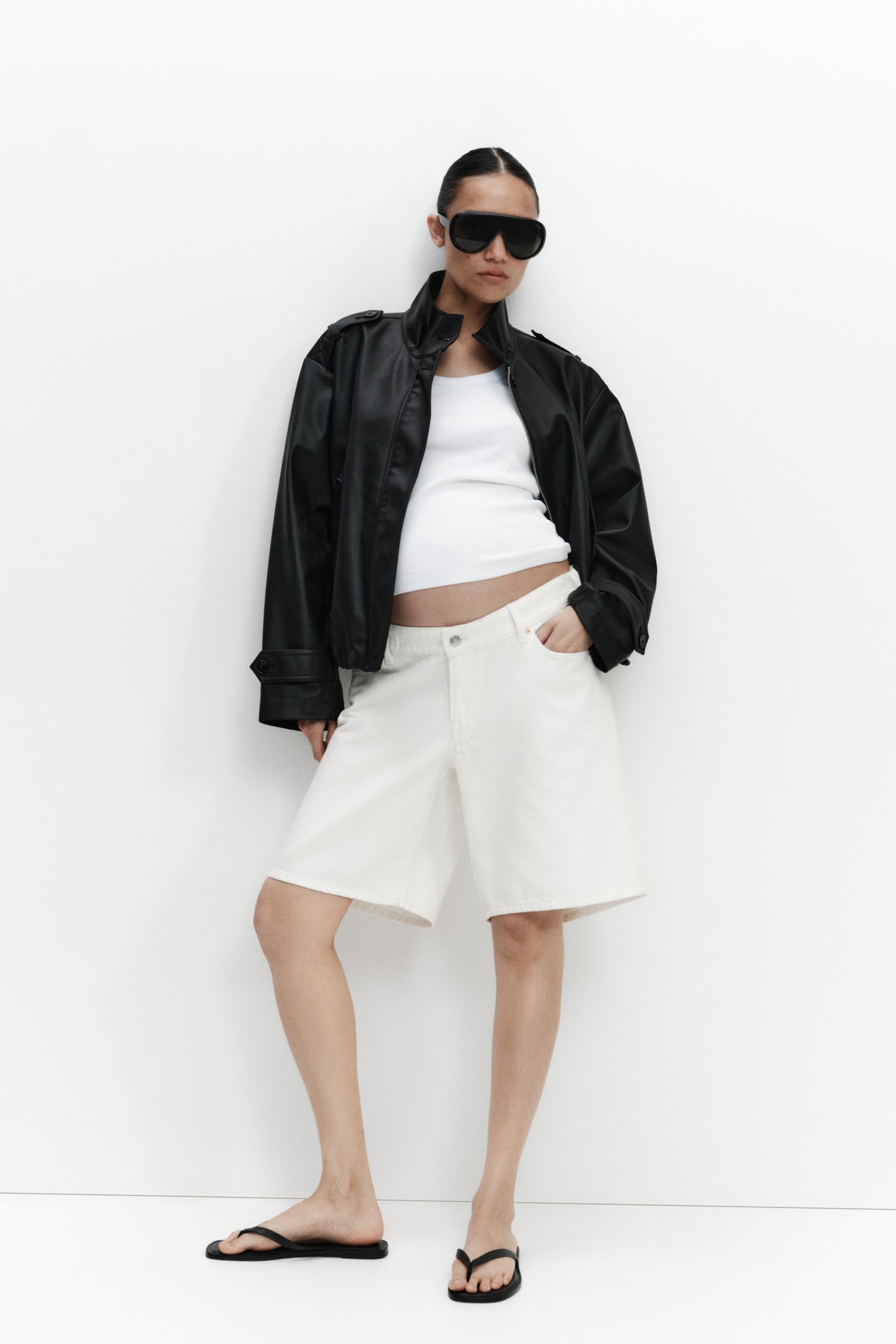 Off-white denim shorts boast a relaxed, wide-leg fit, highlighting a high waistband with elastication at the back and belt loops. They feature a front button and zip fastening, accompanied by front slash pockets adorned with small copper-toned rivets. - 1