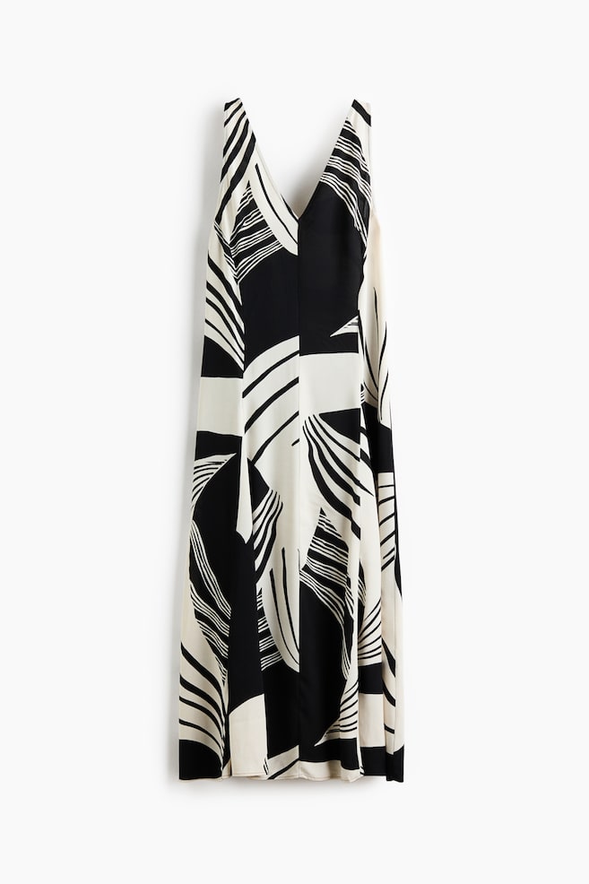 The dress is presenting front, featuring a sleeveless design with a V-neckline. It is showcasing an abstract pattern of bold black and off-white curved and geometric shapes throughout its maxi length. - 1