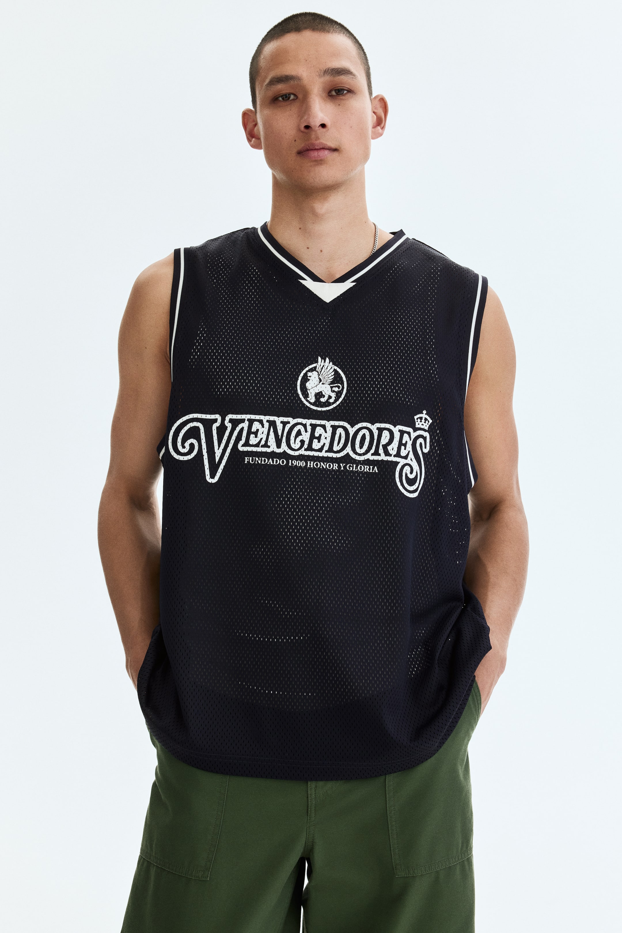 View larger image: A black mesh jersey featuring a V-neck with white and black striped trim and white piping along the armholes. The front showcases a white circular emblem with a winged lion above the text "VENCEDORES," including a crown detail, and smaller text "FUNDADO 1900 HONOR Y GLORIA."