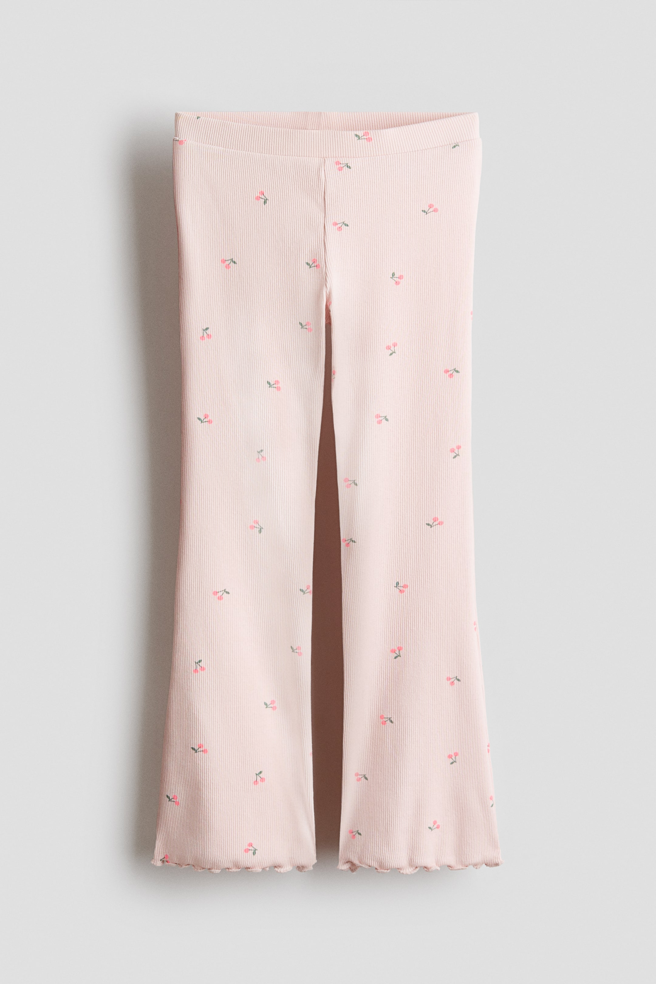 View larger image: Leggings in soft light pink ribbed cotton jersey are showcased at the FRONT, featuring covered elastication at the waist. They display a small cherry motif pattern throughout and finish with flared, ruffled hems.