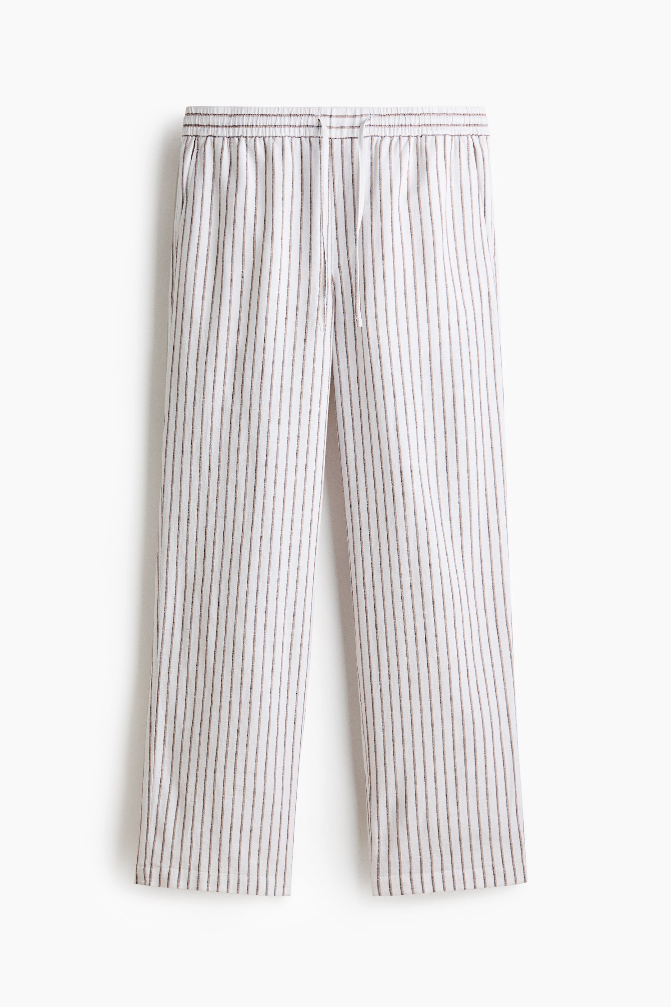 View larger image: The front of the trousers showcases a white fabric adorned with fine dark vertical stripes, featuring a concealed elastic waistband with a white drawstring and angled side pockets. The trousers exhibit a relaxed fit.