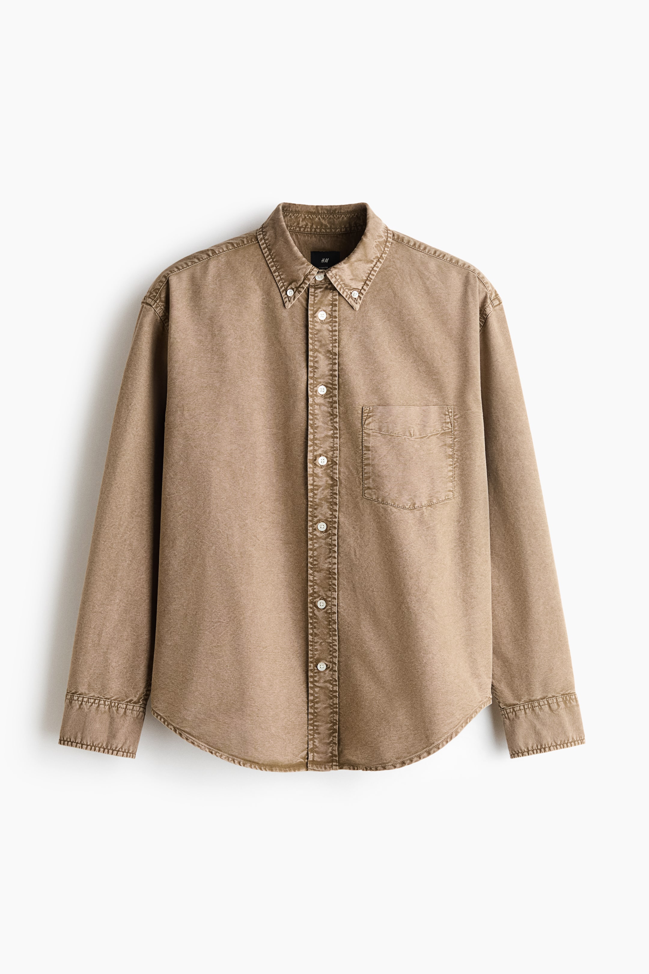 View larger image: A long-sleeved Oxford cotton shirt in a washed tan colour is displayed in a relaxed fit from a front-facing view. It features a button-down collar, a buttoned front placket, a single open chest pocket, and a gently rounded hem.