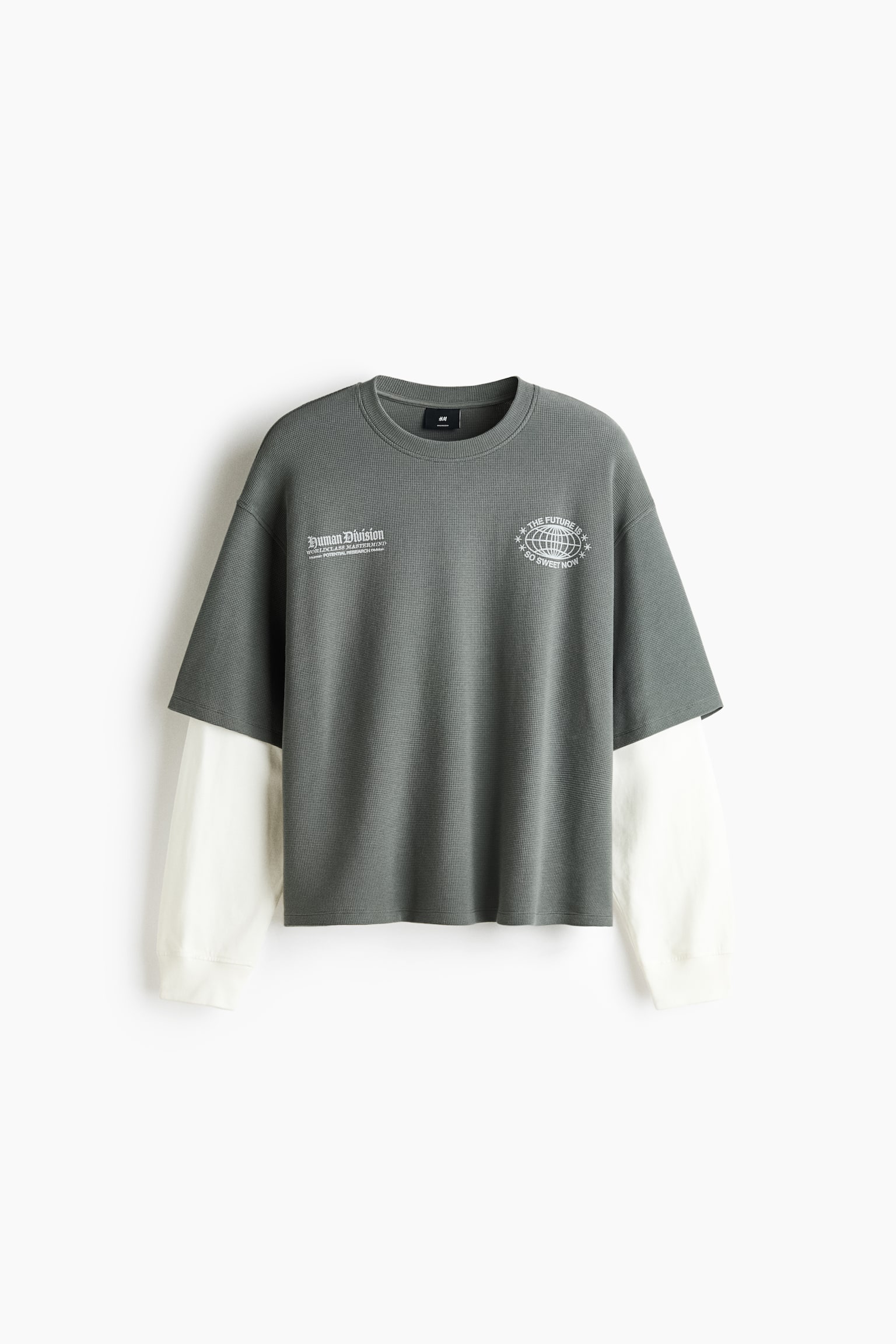 Un t-shirt Ã  manches longues superposÃ© est prÃ©sentÃ© de face, mettant en valeur une couche extÃ©rieure Ã  manches courtes texturÃ©e gris foncÃ©, avec des manches longues crÃ¨me contrastantes dÃ©passant de dessous. La couche extÃ©rieure affiche deux imprimÃ©s graphiques blancs sur la poitrine et prÃ©sente un col rond cÃ´telÃ©, tandis que les manches crÃ¨me se terminent par des poignets cÃ´telÃ©s.