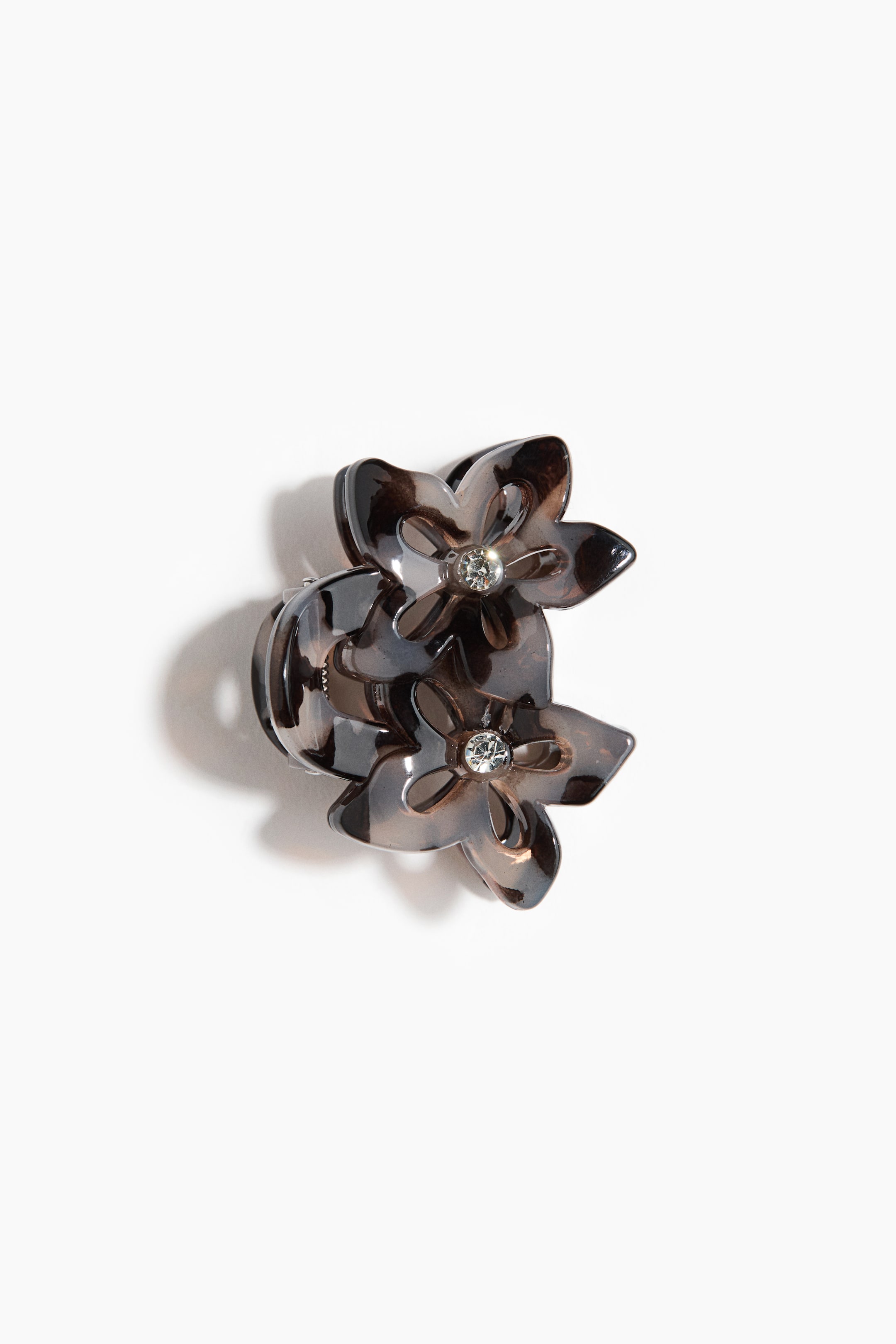 Zobacz większy obraz: Klamra do włosów prezentuje dwa warstwowe, skierowane przodem kwiaty; każdy z nich wykonany jest z półprzezroczystego, brązowo‑czarnego materiału w wzorze „tortoiseshell” i ma na środku przezroczysty rhinestone. Mechanizm klamry jest widoczny bezpośrednio za kwiatami.