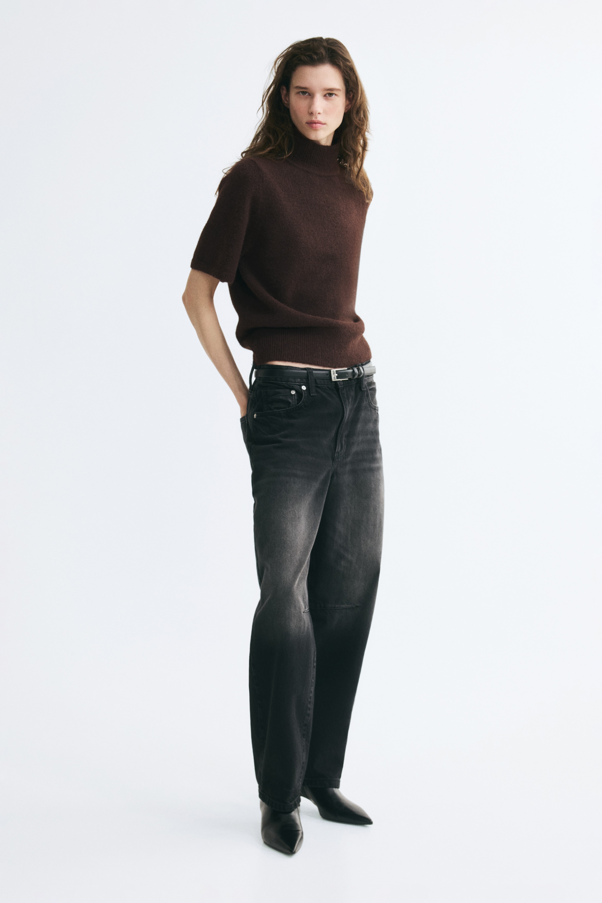 A dark brown, fuzzy knit short-sleeve jumper is shown from the front, featuring a ribbed mock neck and a matching ribbed hem. The top has a soft, textured finish with relaxed, elbow-length sleeves.
