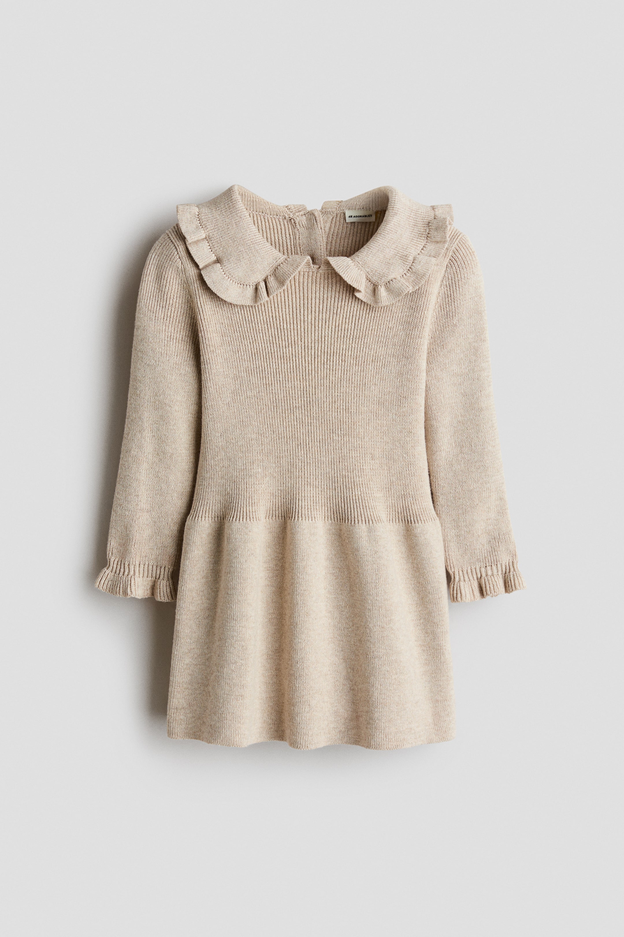 Visualizza l'immagine ingrandita: Un abito in maglia beige presenta un corpino in maglia a costine compatta, un colletto arrotondato rifinito con volant e maniche lunghe con polsini arricciati. L’abito mostra inoltre una gonna svasata e un’apertura visibile sul retro del collo.