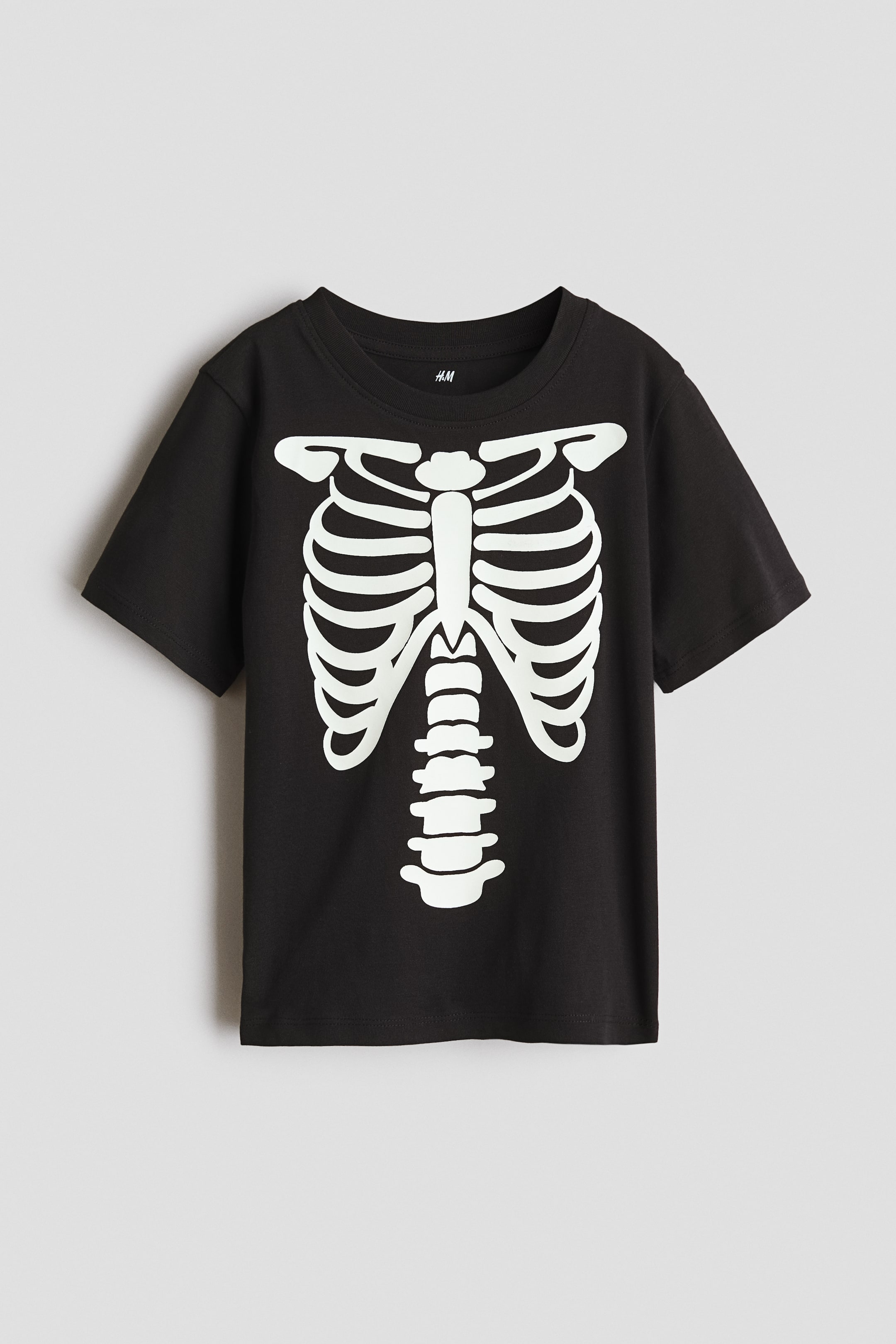 View larger image: A black t-shirt showcasing a white skeleton torso print on its front, complete with a crew neck and short sleeves.