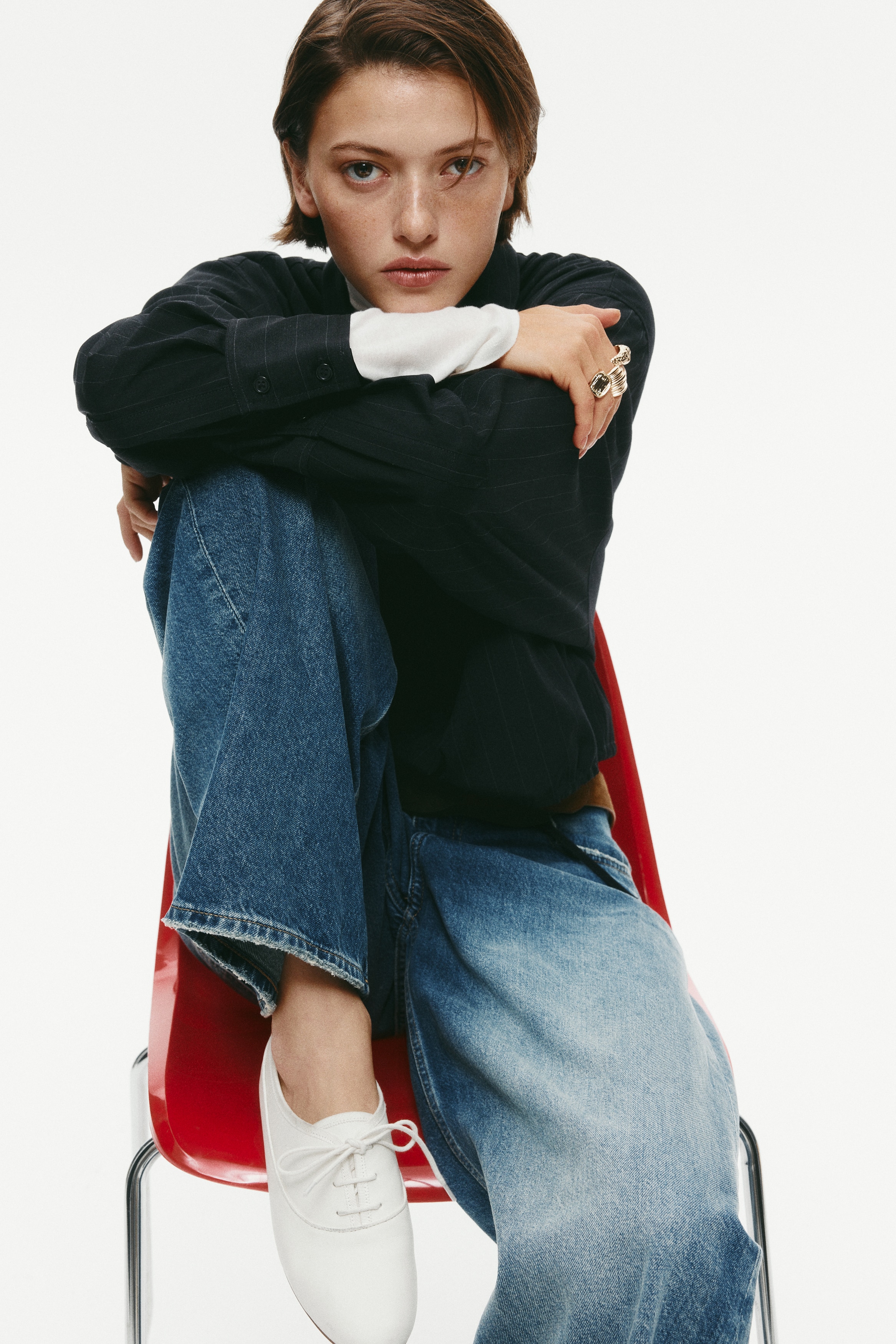 These five-pocket denim jeans are shown from the front, featuring a regular waist and curved, voluminous legs that taper slightly towards the hems. The medium blue wash displays prominent fading across the thighs and knees, accented by subtle worn detailing on the pocket edges and hems.