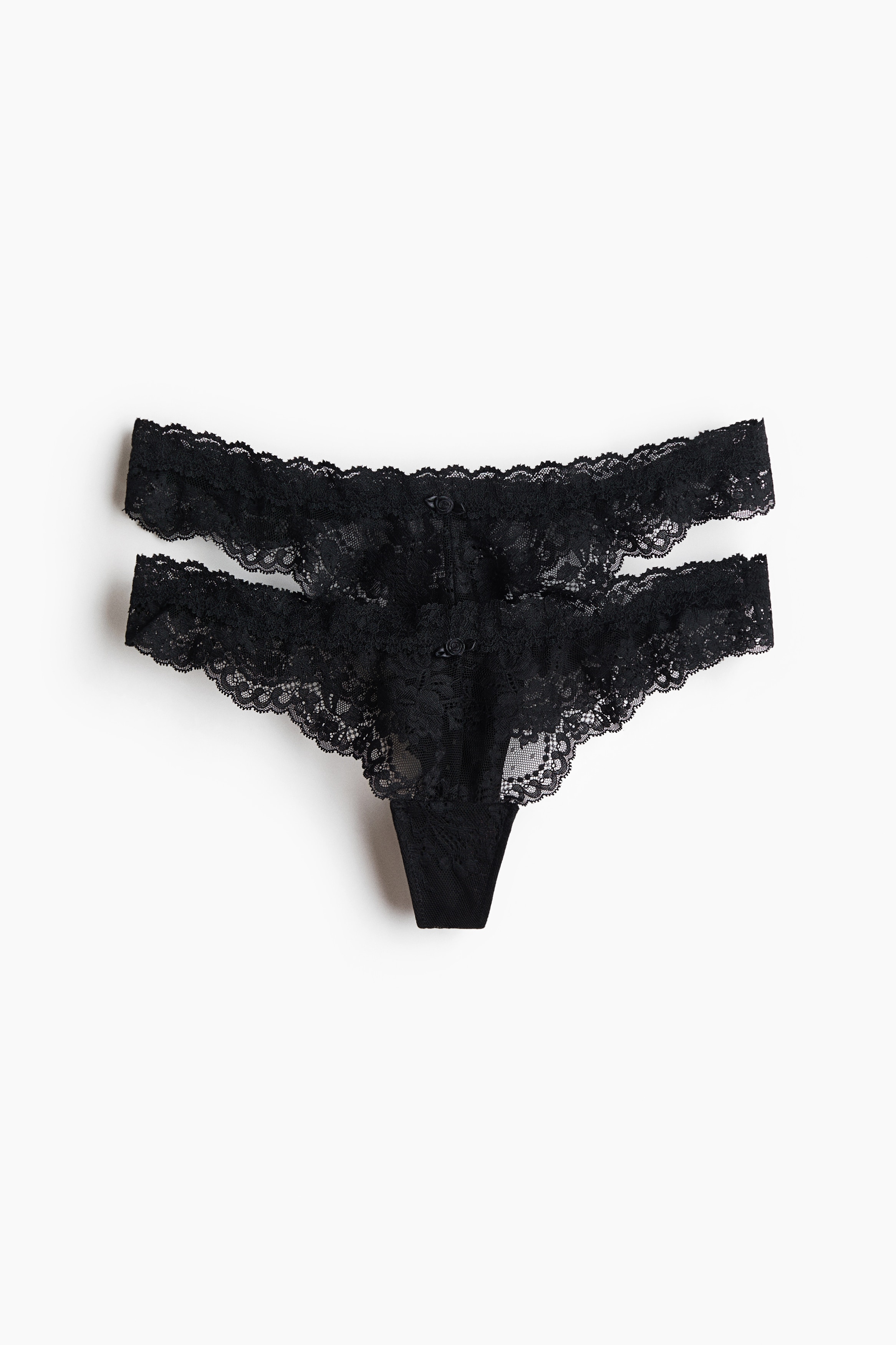 Black lace thong briefs with a low waist are being worn by the model, viewed from behind. A matching black lace bra is also being worn, coordinating with the briefs.