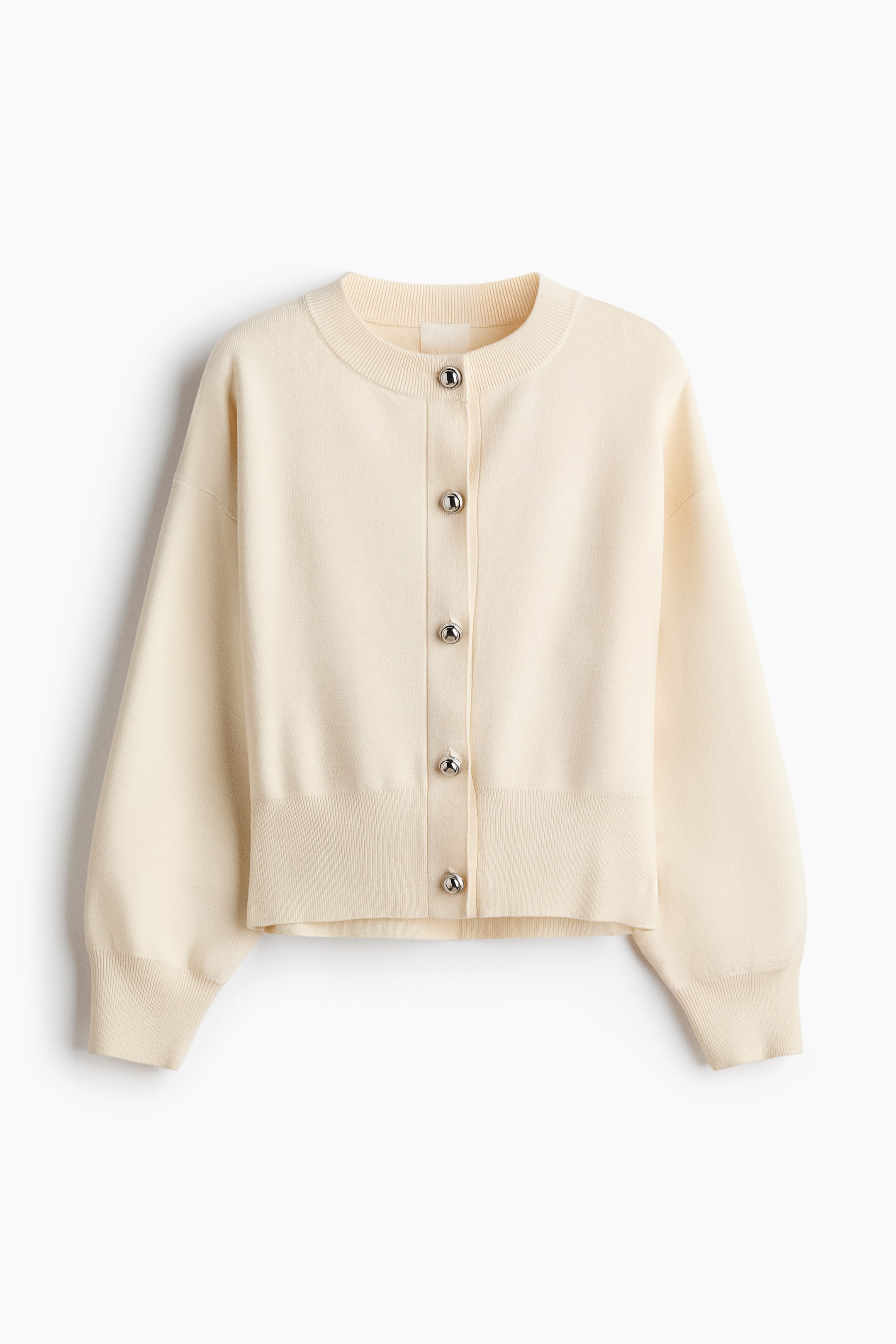 View larger image: A cream-colored fine-knit cardigan is shown from the front, featuring a round rib-trimmed neckline, dropped shoulders, and five silver-tone dome buttons down the center front. The cardigan has long sleeves with wide ribbed cuffs and a matching ribbed hem.