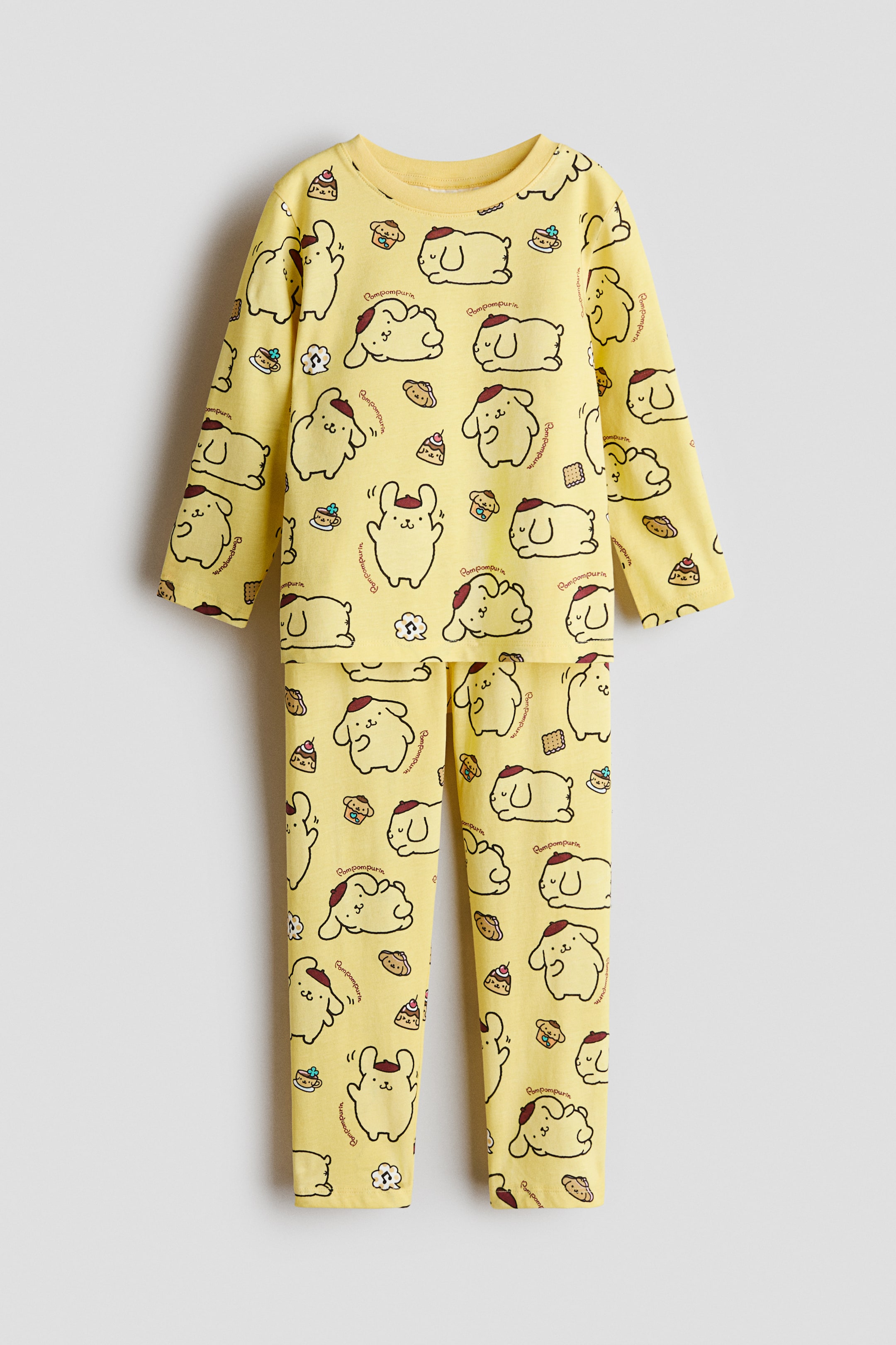 View larger image: A pajama set is presented with a long-sleeved top featuring a round neck and matching long pants, shown from the front. The yellow set showcases an all-over print of Pompompurin characters and various dessert items.