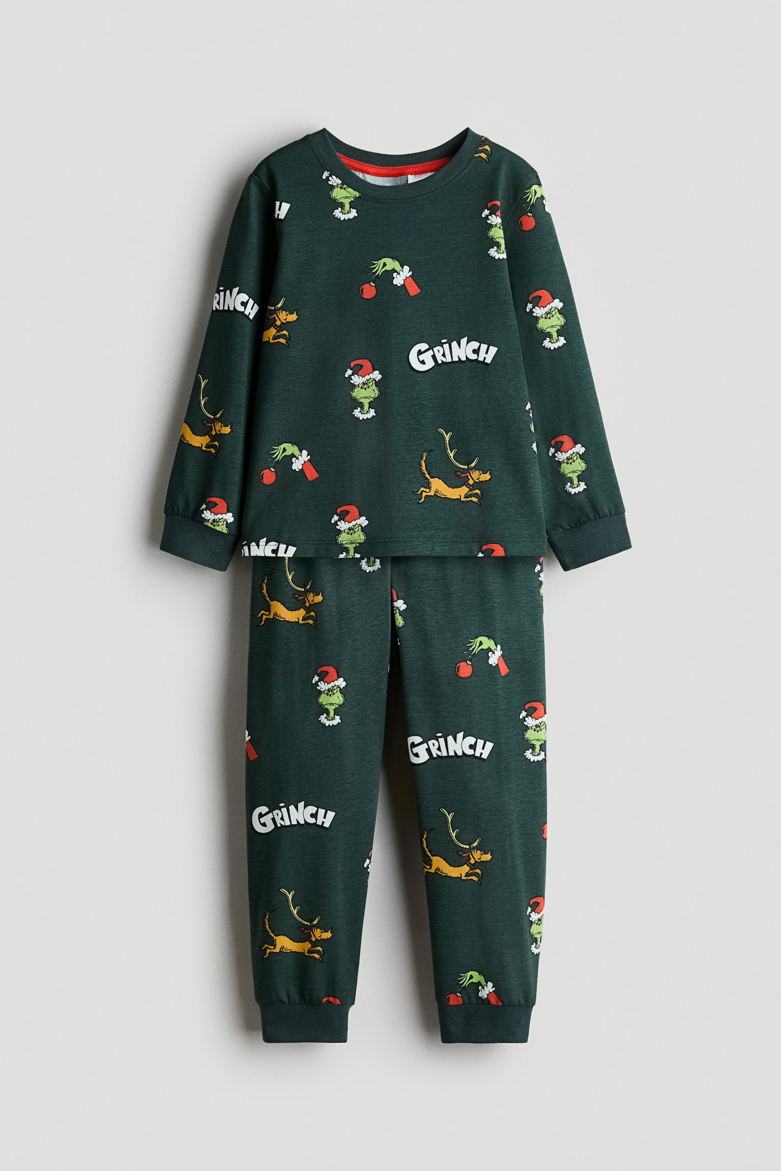 Ein dunkelgrÃ¼nes Pyjama-Set wird von vorne gezeigt und besteht aus einem langÃ¤rmeligen Oberteil und einer passenden Hose mit einem Allover-Print aus Grinch-inspirierten Figuren und SchriftzÃ¼gen. Das Oberteil ist mit einem gerippten Rundhalsausschnitt und gerippten ÃrmelabschlÃ¼ssen gestaltet, wÃ¤hrend die Hose Ã¼ber einen elastischen Bund und gerippte BeinabschlÃ¼sse verfÃ¼gt.