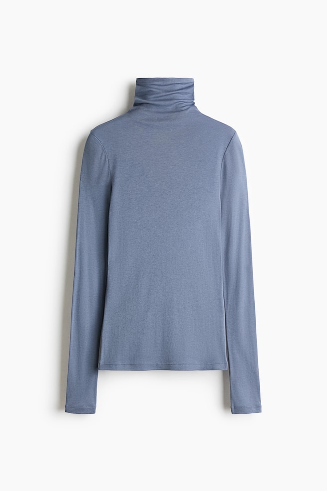 A long-sleeved top in soft, dusty blue jersey is hanging facing front, featuring a high, slouchy roll neck and extra-long slim sleeves that extend past the straight hemline. - 1