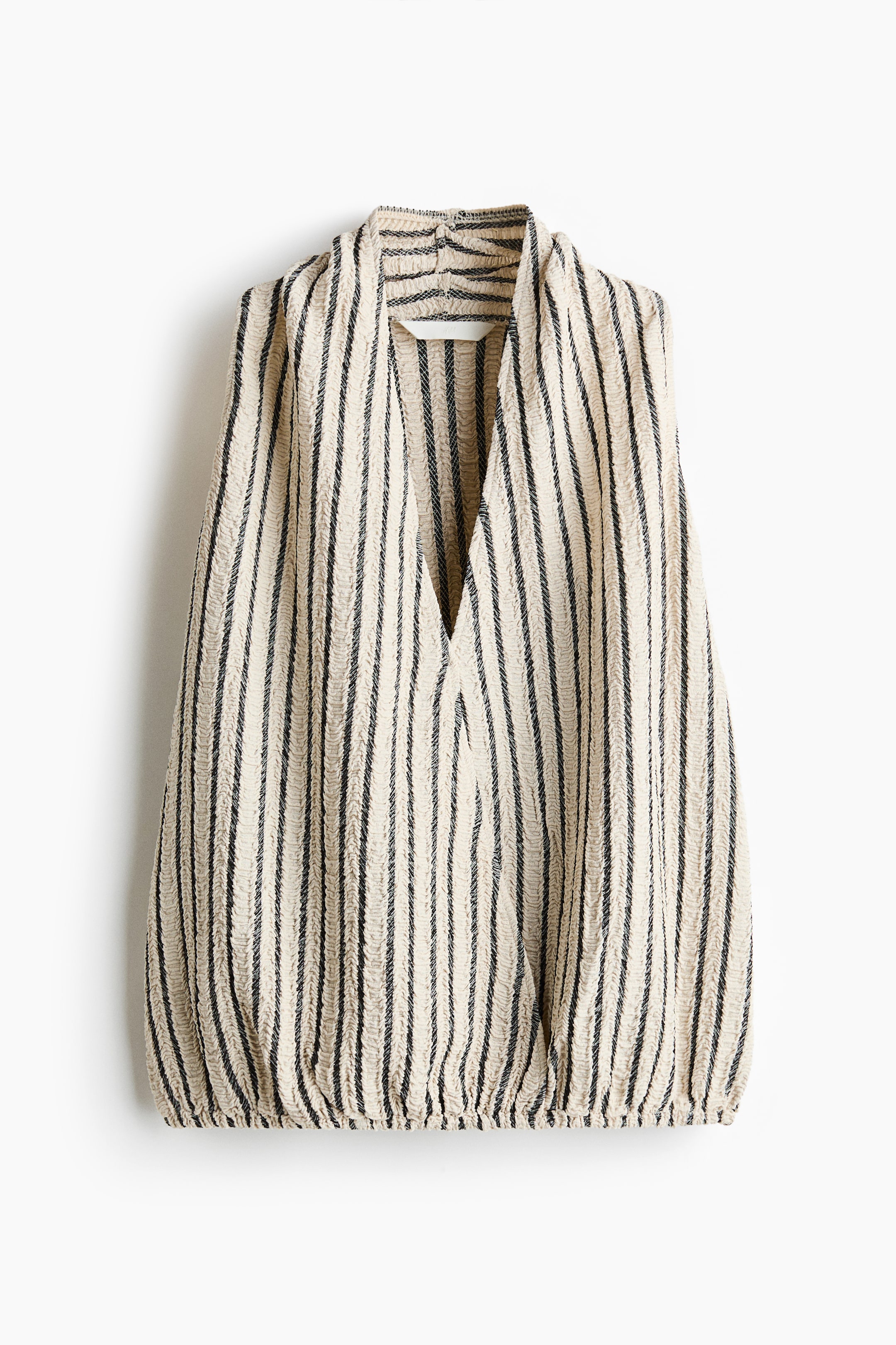 View larger image: A sleeveless striped top is showcasing its front view, featuring a beige crinkled fabric with vertical black stripes and a draped V-neckline. The bottom hem is gathered, creating a blouson shape.