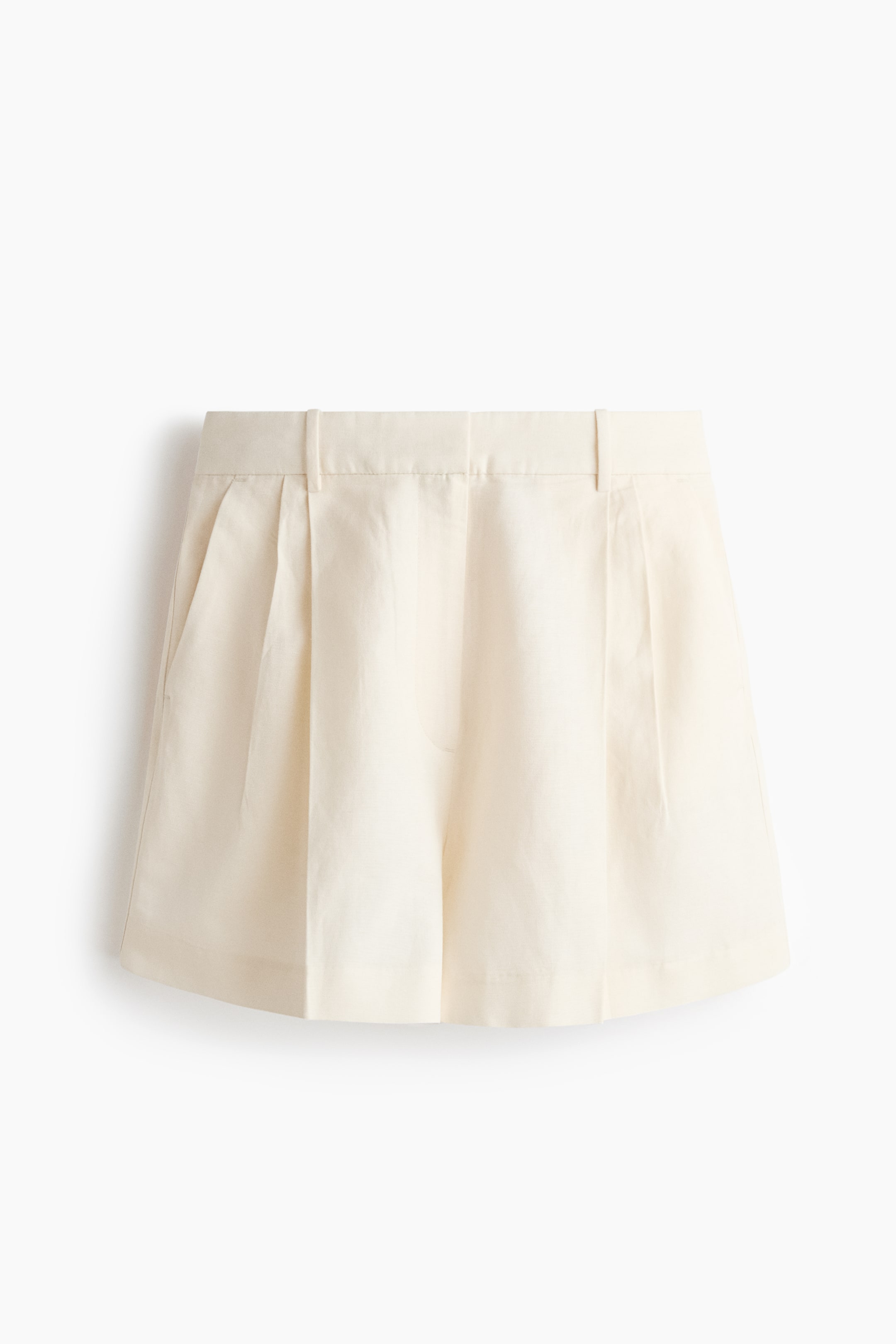 View larger image: Cream-colored shorts are shown front-facing, featuring a flat waistband with belt loops. They display front pleats on each leg and angled side pockets.