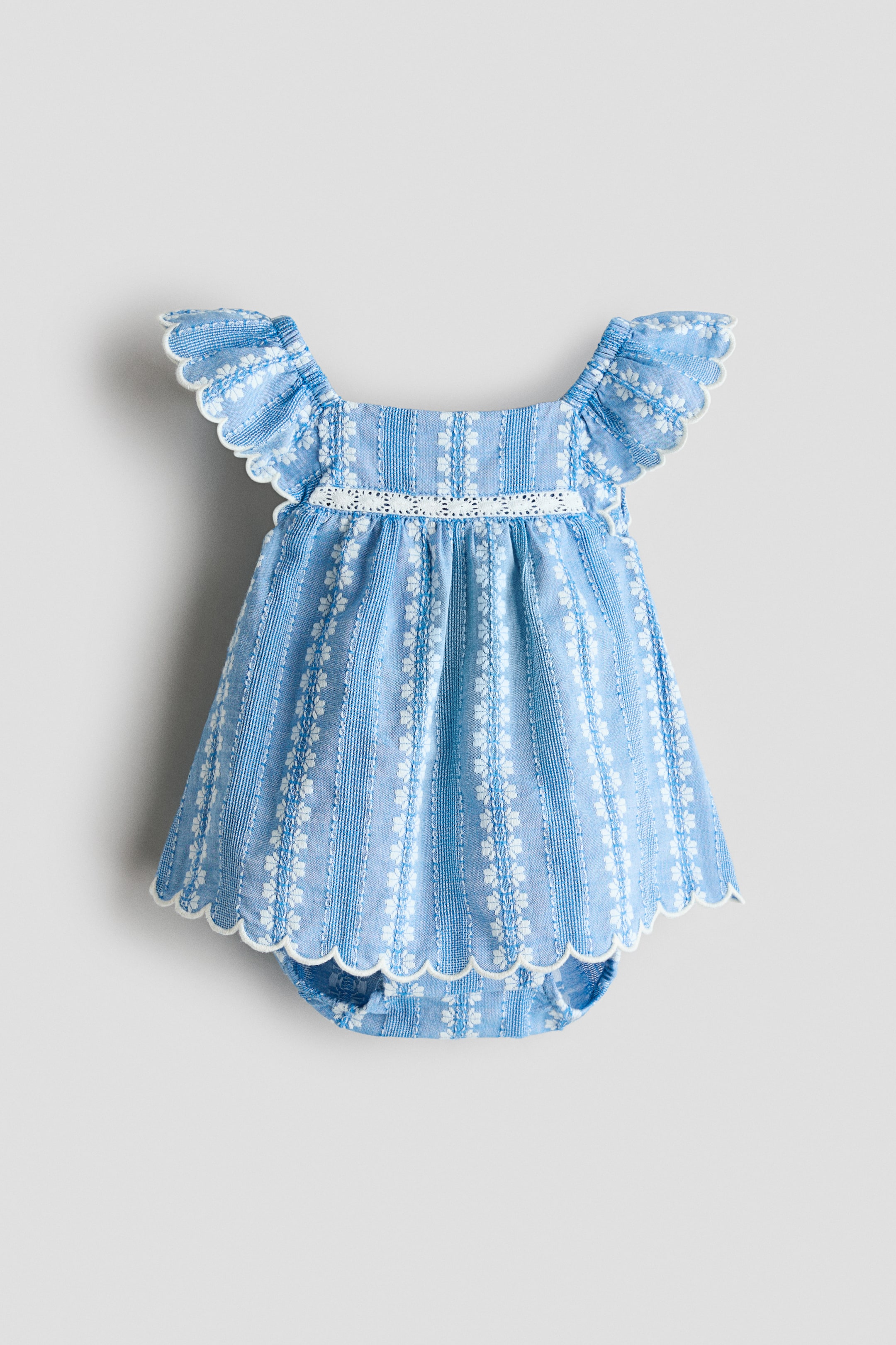 Größeres Bild anzeigen: Ein blau-weißes Baby-Kleid-Set präsentiert einen quadratischen Ausschnitt und kurze, flatternde Ärmel mit weißem Zierbesatz. Das Kleid zeichnet sich durch vertikale Streifen aus blauem Stoff und weißer Blumenstickerei aus, einen weißen Spitzenbesatz an der gerafften Taille und einen gewellten Saum, mit passenden Bloomers, die darunter sichtbar sind.