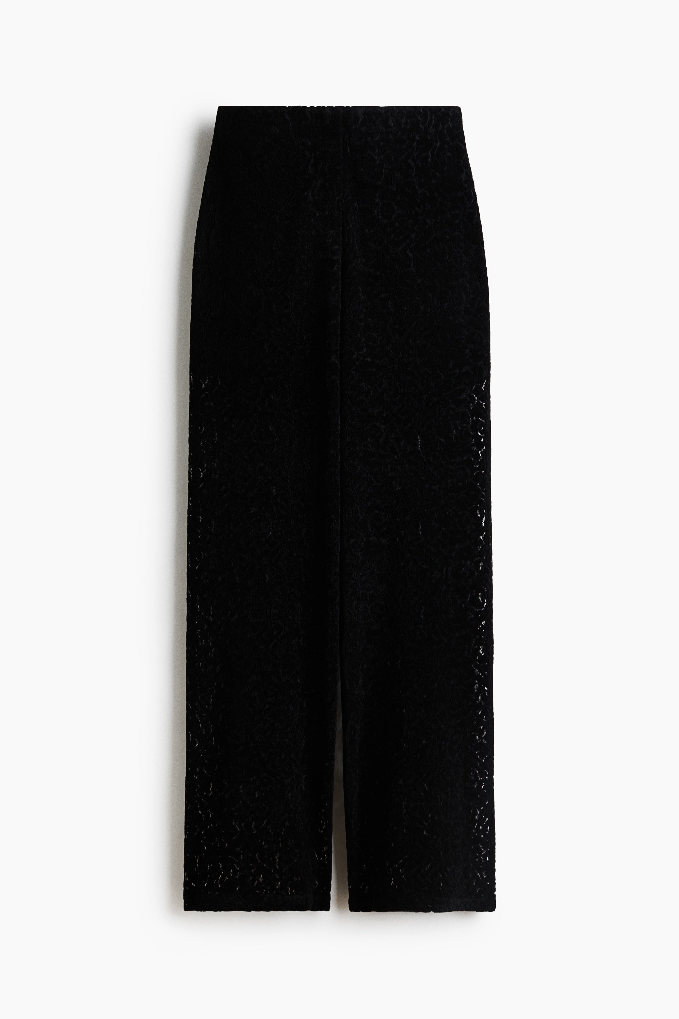 Un pantalon en dentelle à jambes larges et à texture ajourée à motif est porté par le mannequin. Le pantalon est associé à une chemise blanche déboutonnée.