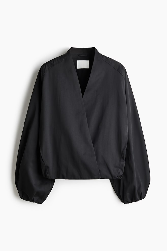 A black wrap-front top is shown from the front, featuring a deep V-neckline, voluminous balloon sleeves with gathered cuffs, and an elasticated hem. - 1