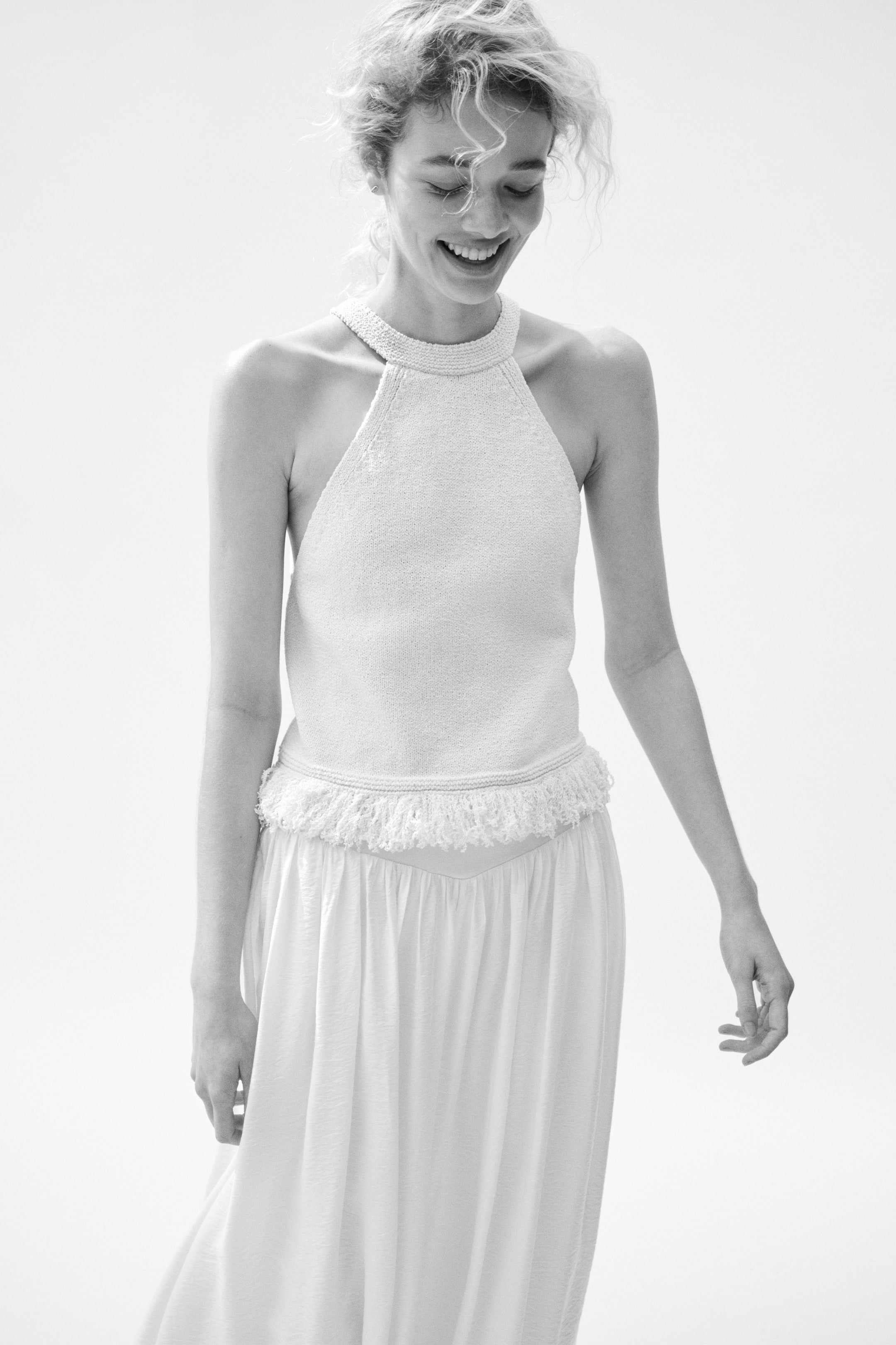 View larger image: Presenting a knitted halter top paired with a flowing maxi skirt. The top showcases a high, beaded halter neckline and a fringed hemline, elegantly layered over the skirt's V-shaped waist.
