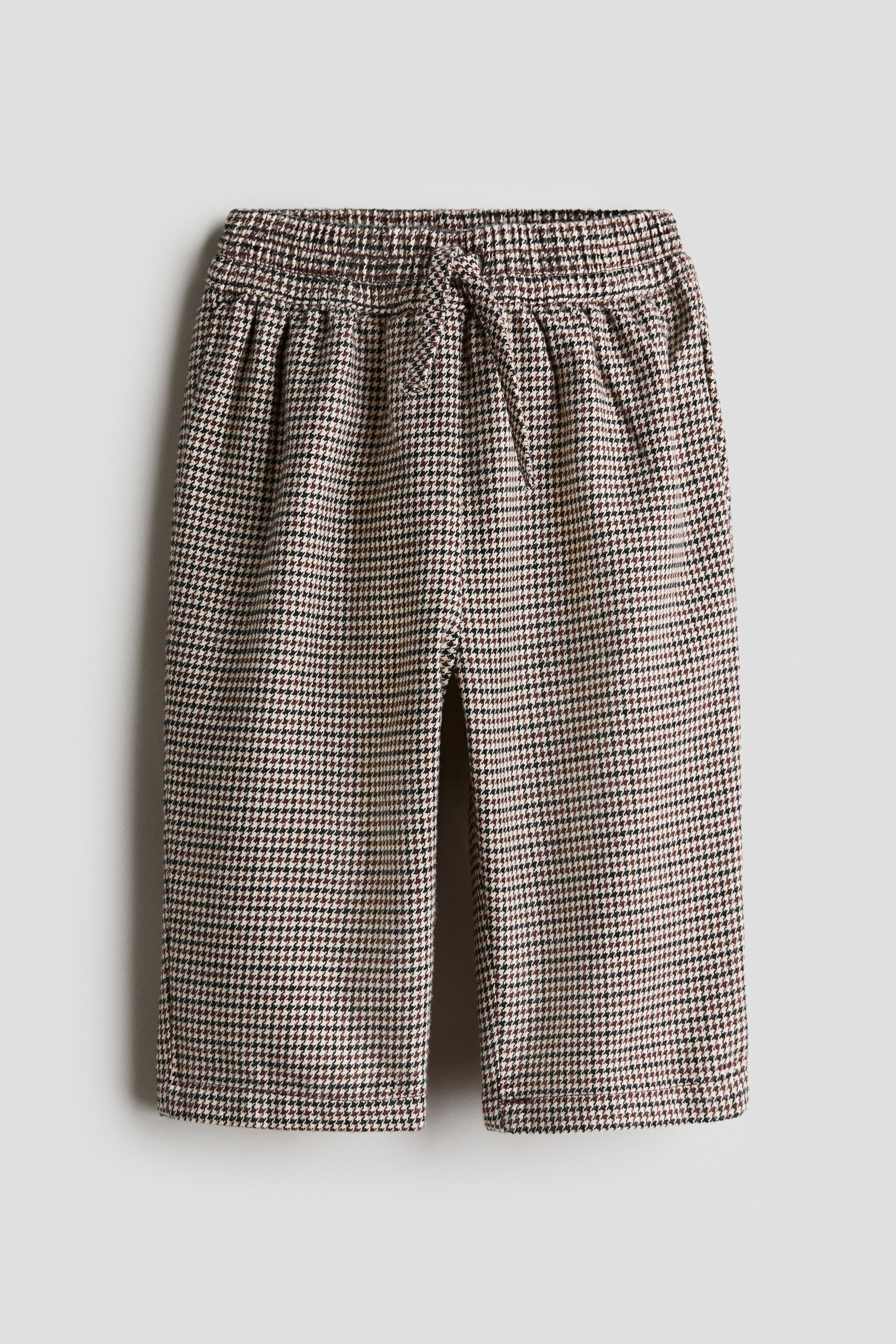 Grösseres Bild ansehen: Die Hose präsentiert ein braun-schwarz-beiges Hahnentrittmuster, von vorne betrachtet. Sie verfügt über einen elastischen Bund mit Kordelzug und entspannten, verkürzten Beinen.