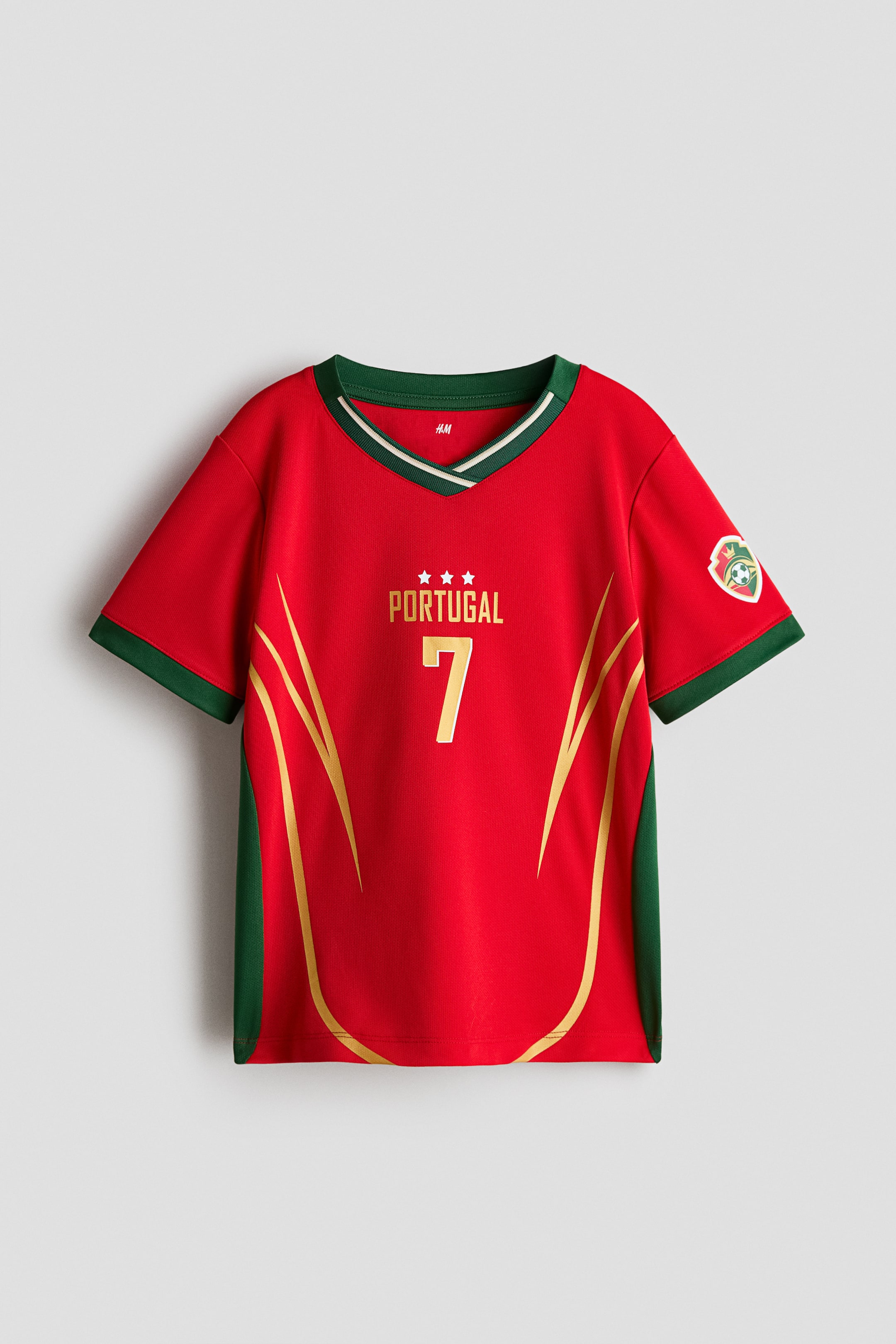 Vis større bilde: En kortermet fotballtrøye i trykt mesh viser sin FORSIDE, med en mørkegrønn ribbekantet V-hals med en hvit stripe, mørkegrønne sidepaneler og ermekanter. Gullfarget 'PORTUGAL'-tekst, tre stjerner og tallet '7' vises på brystet, sammen med buede gulldesignlinjer og et skjoldemblem på høyre erme.