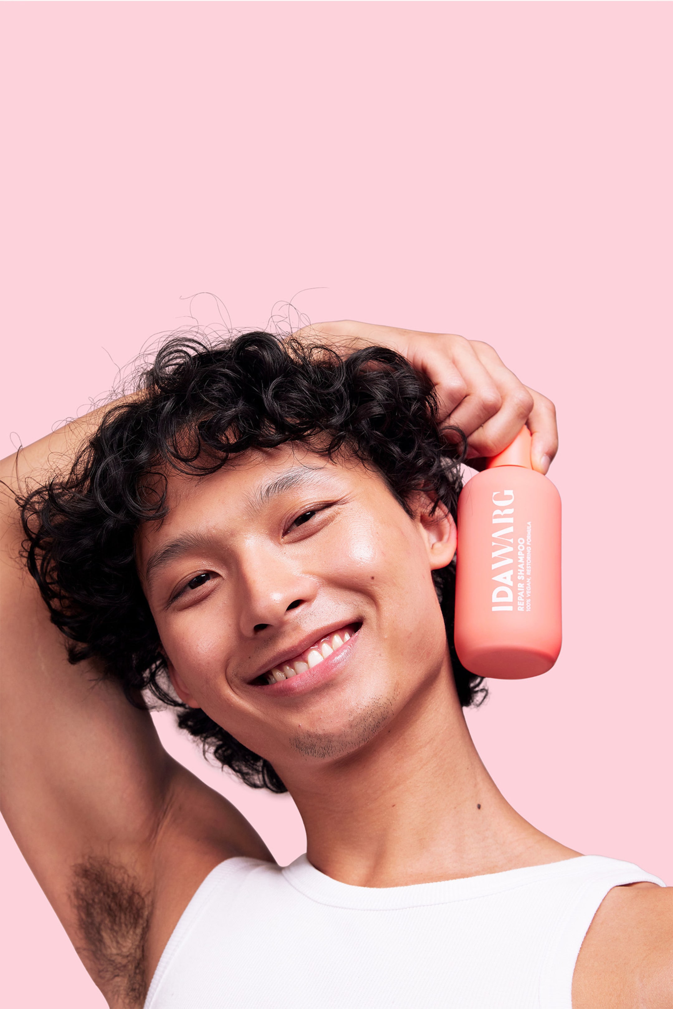 Visa större bild: En korallfärgad, rundad schampoflaska hålls upprätt av en hand, med etiketten vänd framåt. Etiketten visar tydligt "IDAW�RG REPAIR SHAMPOO", "100% VEGAN" och "RESTORING FORMULA".