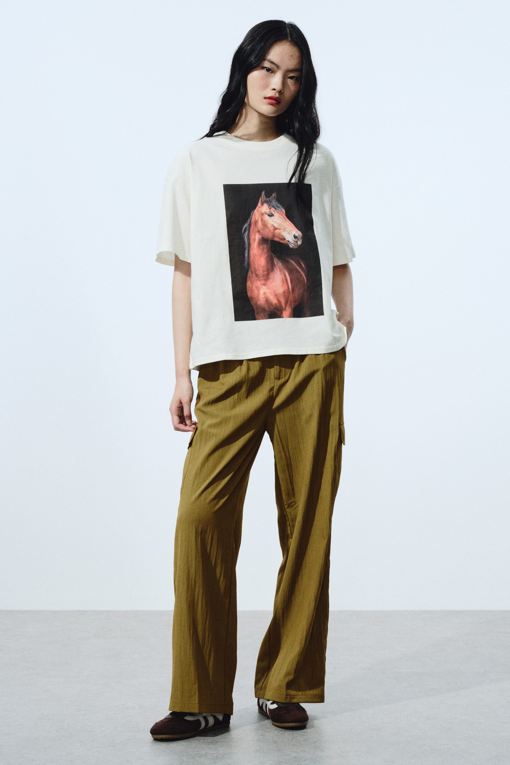 View larger image: An off-white T-shirt features a large rectangular graphic of a brown horse facing right against a dark background, centred on the front. The T-shirt has short sleeves and a crew neck, with a relaxed fit and subtly textured fabric.