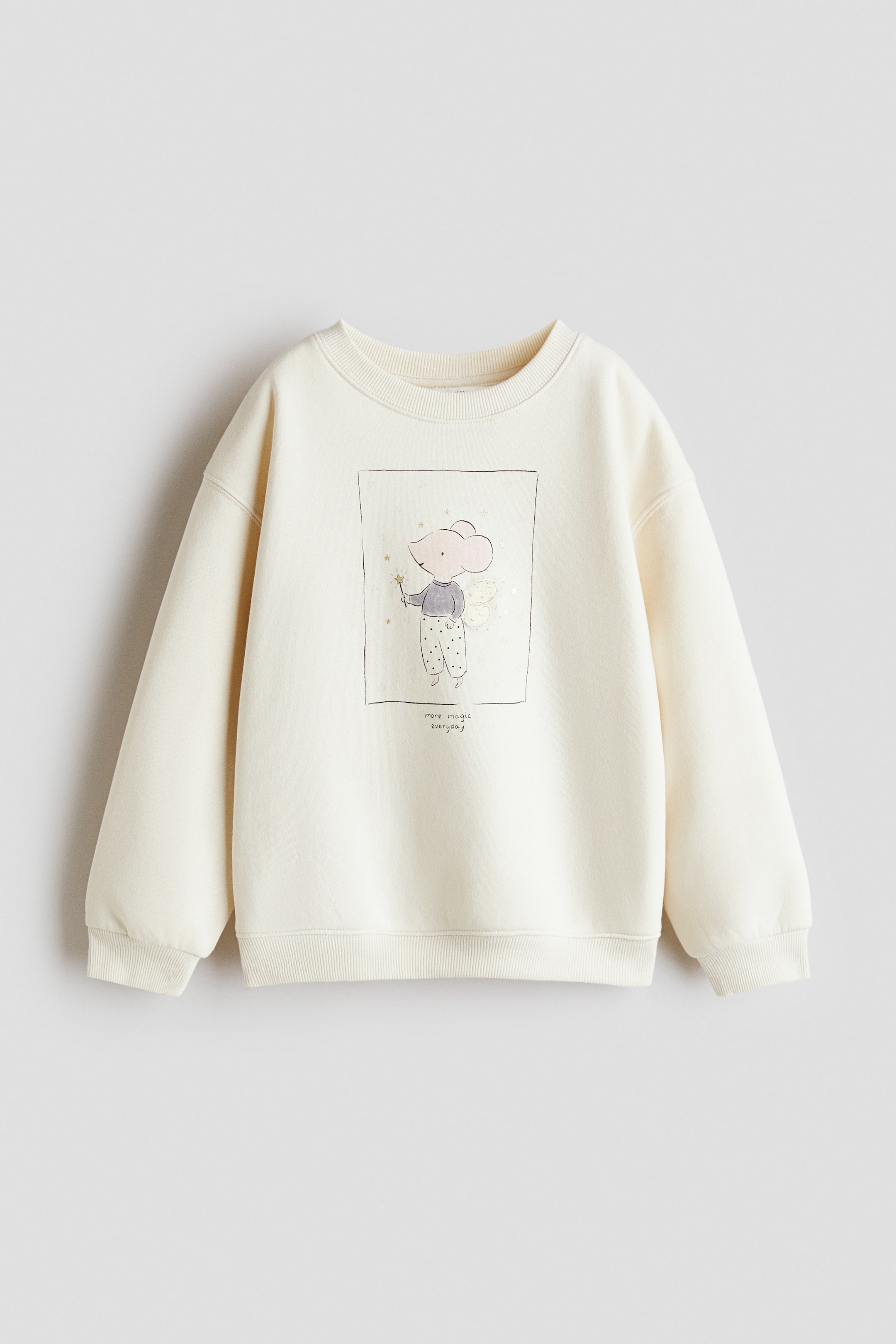 View larger image: A cream sweatshirt is shown from the front, featuring a graphic of a winged mouse holding a wand with the text "more magic everyday" below. It is designed with a round ribbed neckline, dropped shoulders, and ribbed cuffs and hem.