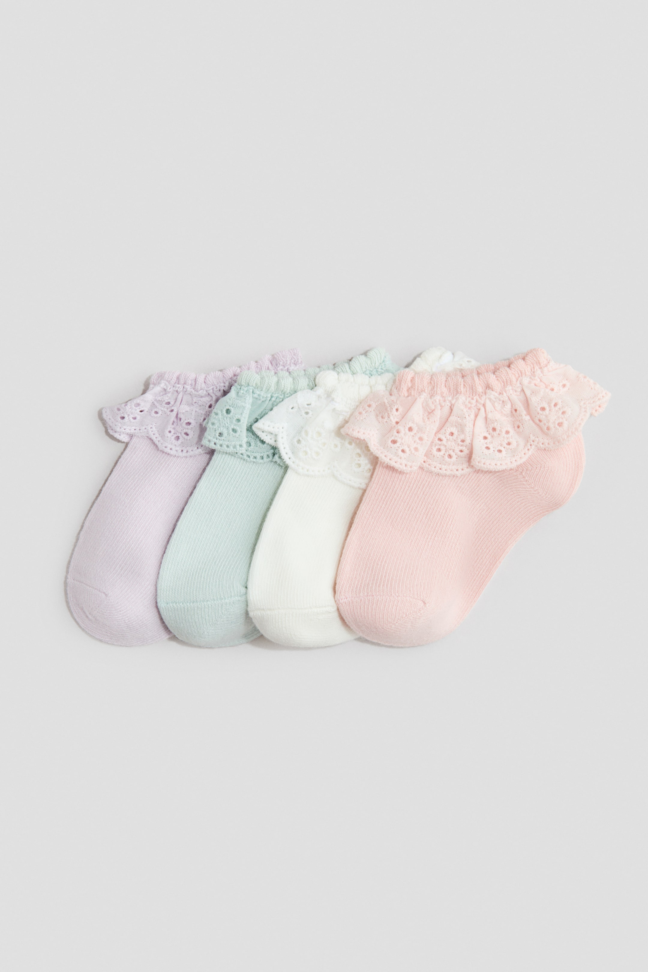 View larger image: Four shaftless socks crafted from a soft, fine-knit cotton blend are neatly arranged side by side. Each pair features an elasticated top adorned with a delicate ruffled eyelet lace detail. The socks come in soothing pastel shades of lavender, mint green, white, and pink.