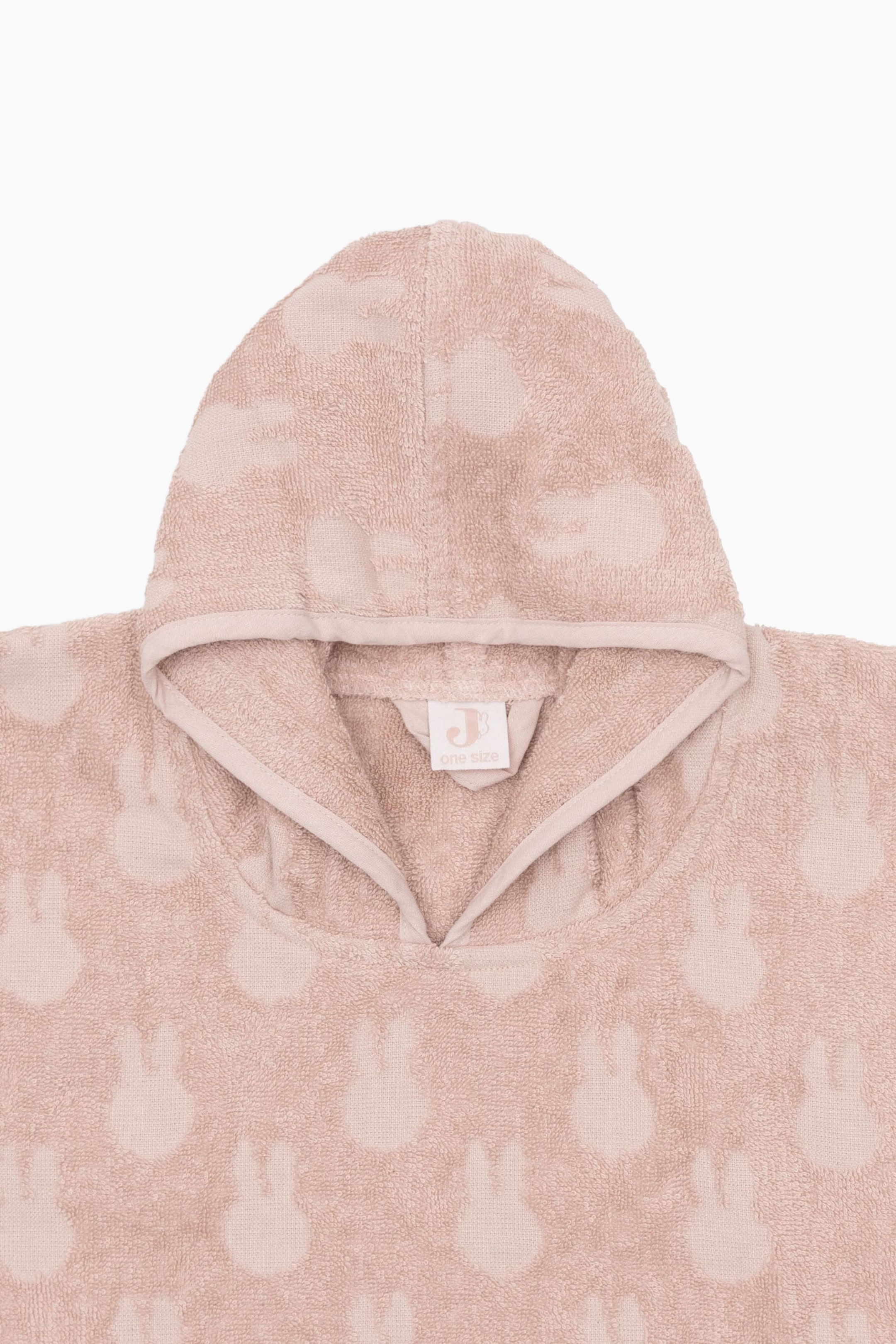 View larger image: A light pink hooded terry cloth poncho is lying flat, featuring an all-over debossed pattern of bunny rabbits. The poncho is showing a V-neck opening with a white brand label visible inside the neck.