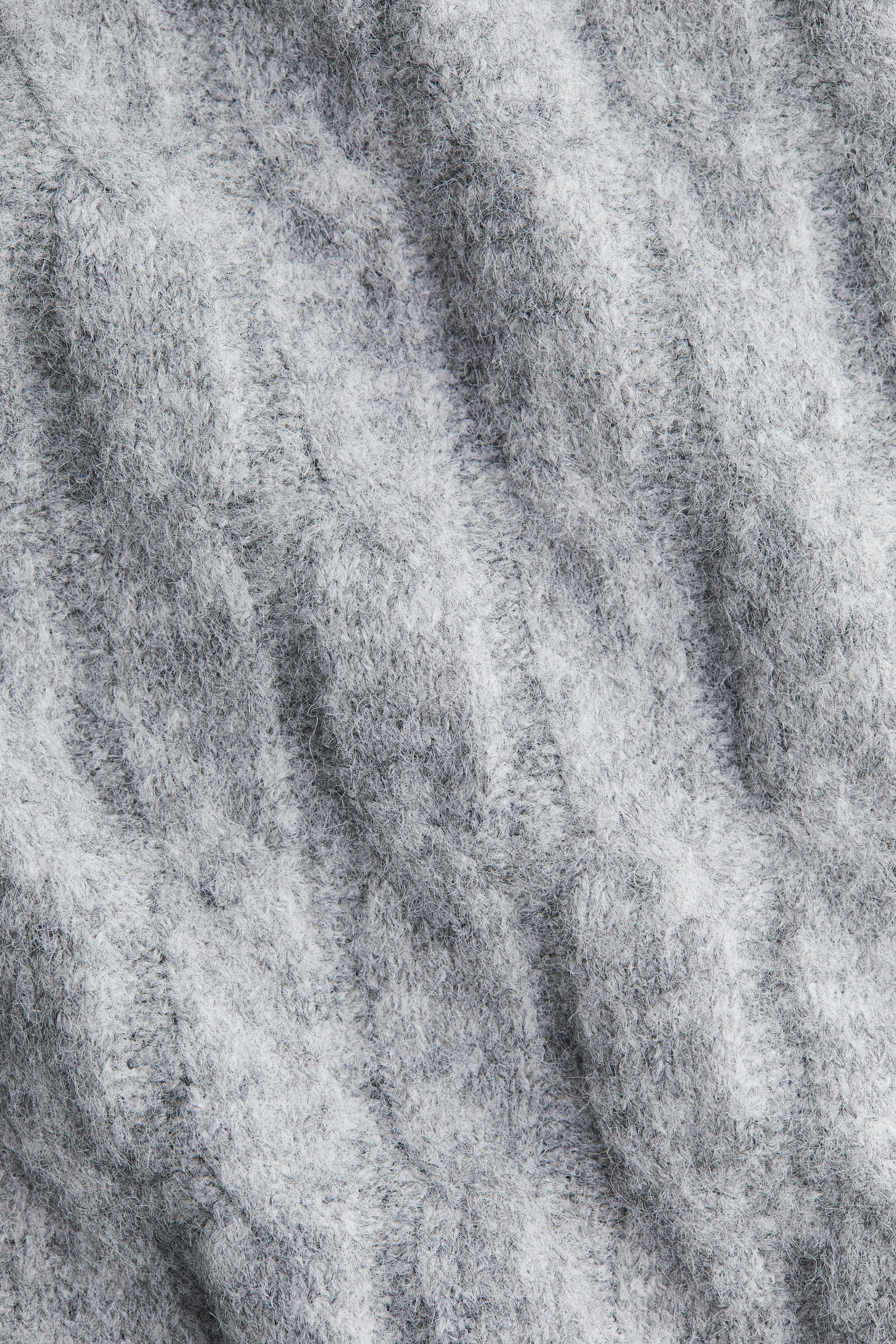 Agrandir l'image: Un tissu tricoté gris chiné présente un motif côtelé proéminent. Le tissu affiche une texture douce et duveteuse avec des crêtes verticales visibles.