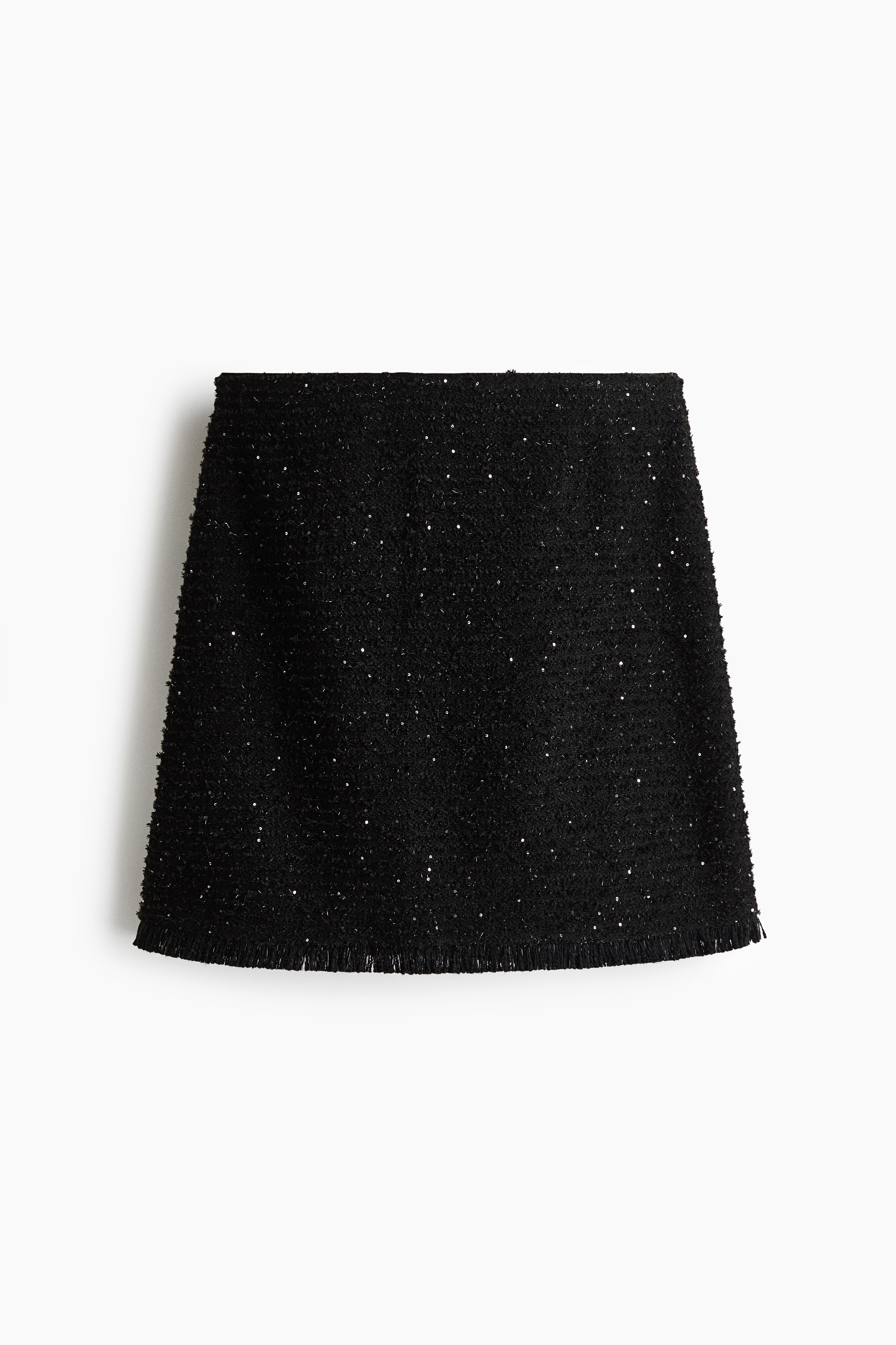 A black textured tweed matching set featuring a sleeveless top and an A-line mini skirt with subtle silver speckles is being worn by the model. The model is carrying a black leather tote bag under one arm and wearing black pointed-toe heels.