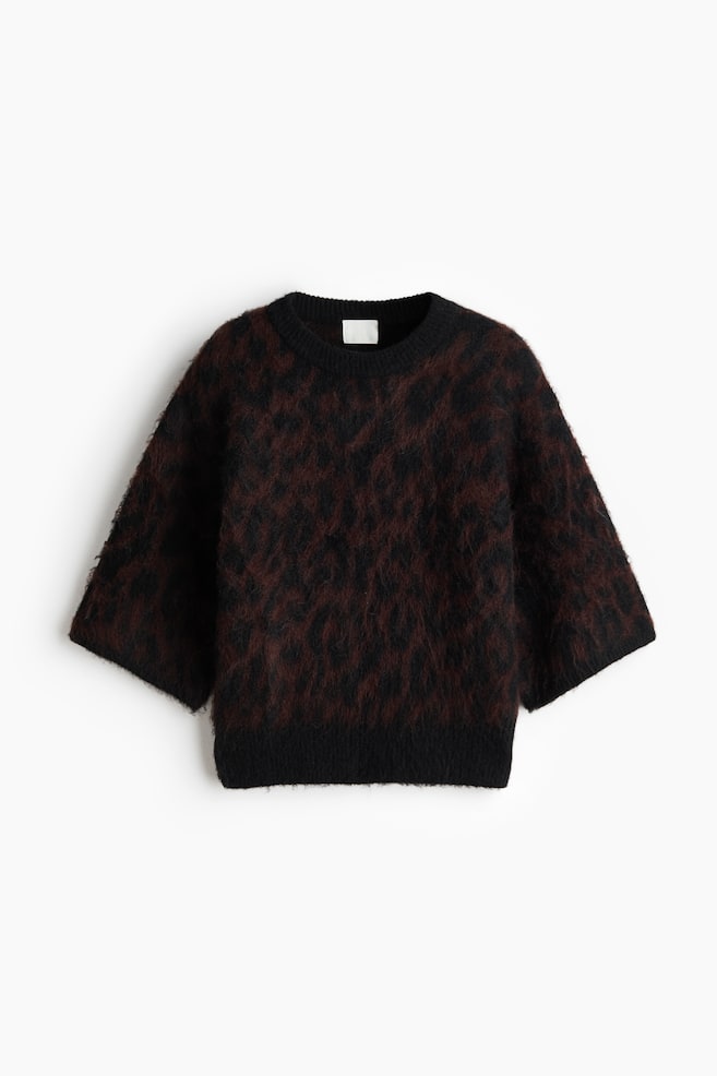 A fuzzy sweater, featuring an irregular reddish-brown pattern over a black base, is lying flat and facing forward, showcasing a crew neck, wide three-quarter sleeves, and a ribbed bottom hem. - 1