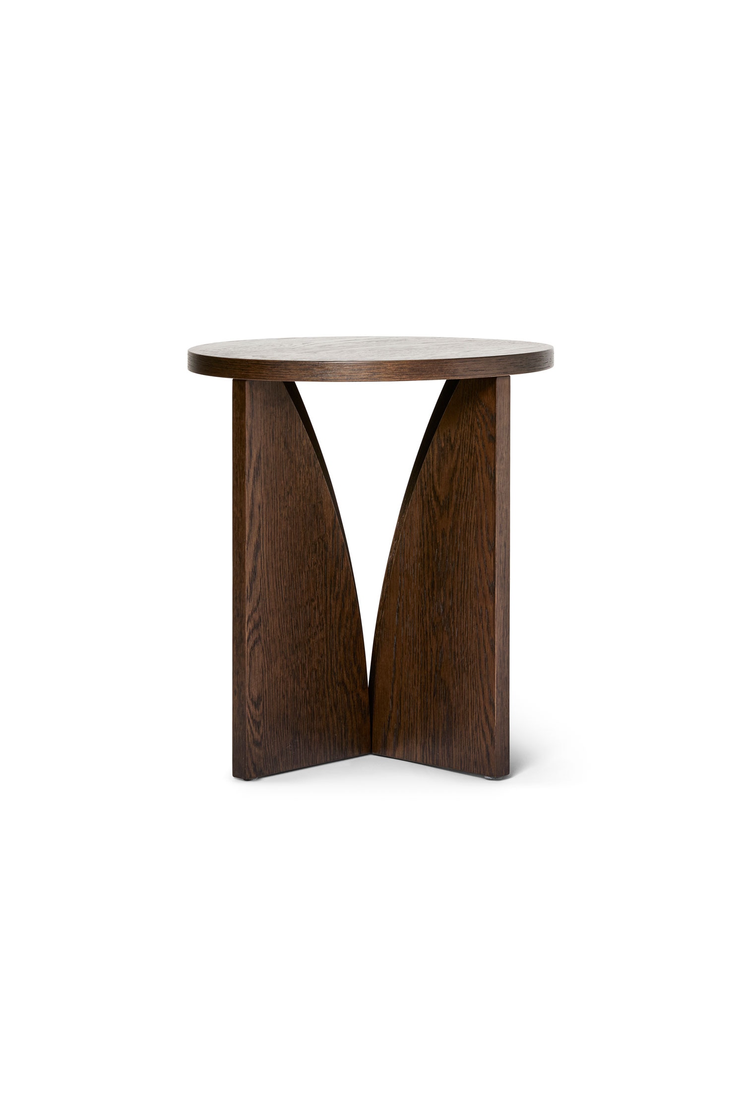 Ein dunkel gebeizter Holz-Beistelltisch mit einer runden Tischplatte auf einem skulpturalen Sockel aus drei ineinandergreifenden, geschwungenen Holzpaneelen. Auf der OberflÃ¤che des Tisches stehen eine kleine Keramikschale mit Popcorn, eine passende Tasse mit einem LÃ¶ffel sowie eine kleine grÃ¼ne Glasvase.