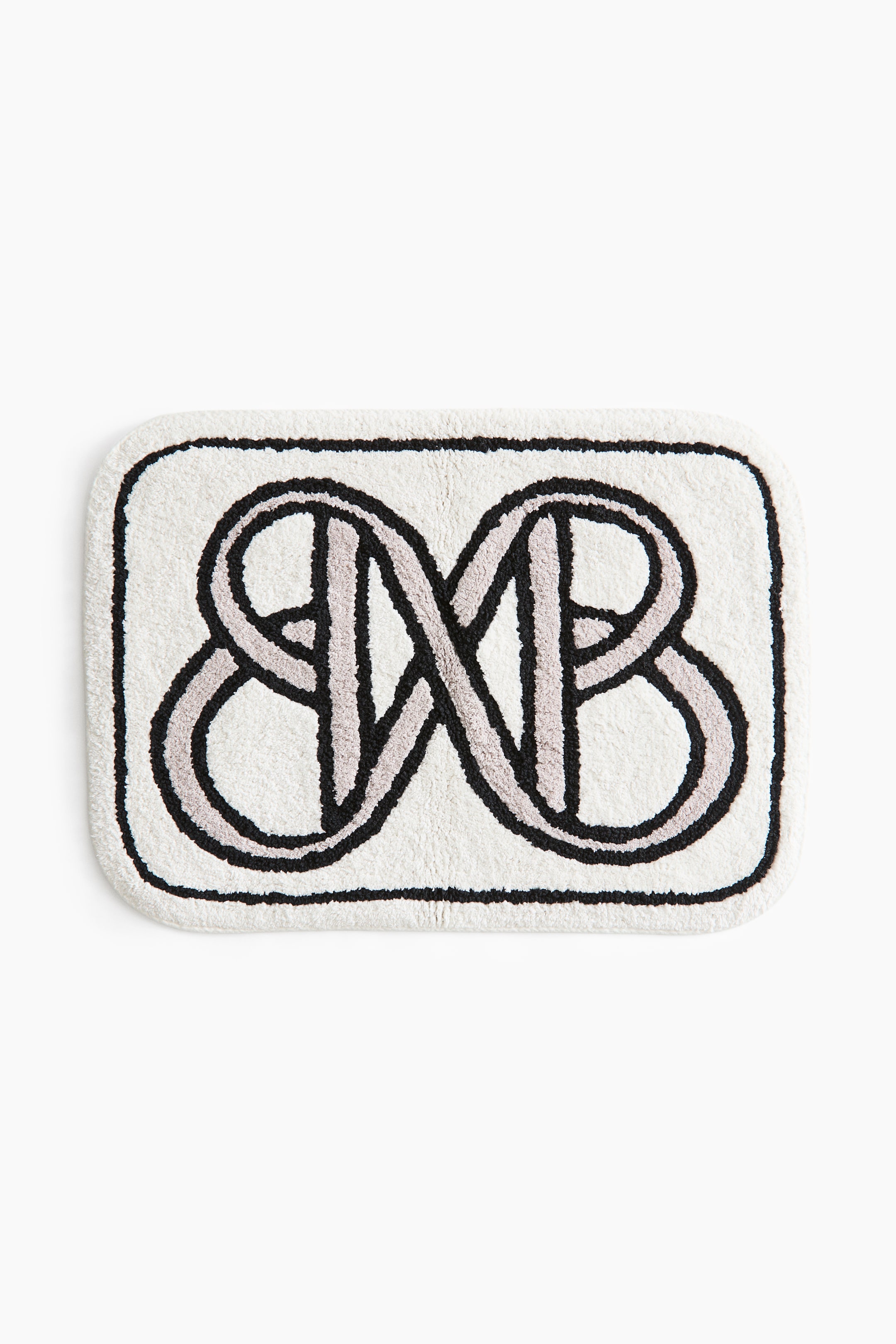 View larger image: A rectangular white bath mat with a tufted texture showcases a prominent central graphic pattern of interlocking black and light grey lines, complemented by a solid black border outlining its rounded corners.