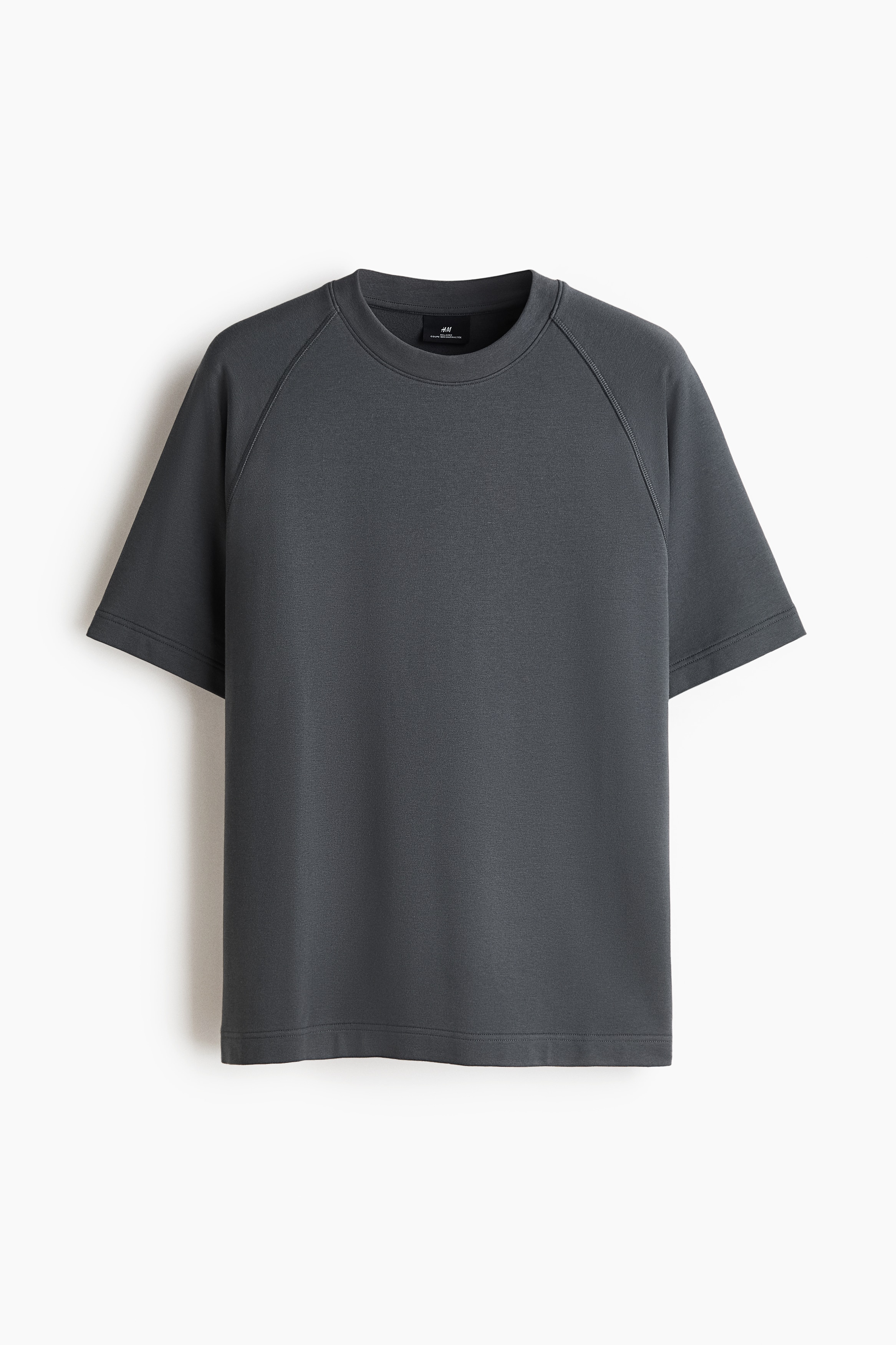 Un t-shirt en jersey Ã©pais gris foncÃ©, Ã  coupe dÃ©contractÃ©e, dotÃ© dâun col rond Ã  bord-cÃ´te et de manches raglan courtes, est portÃ© par le mannequin. Le t-shirt est agencÃ© Ã  un bas assorti gris foncÃ©.