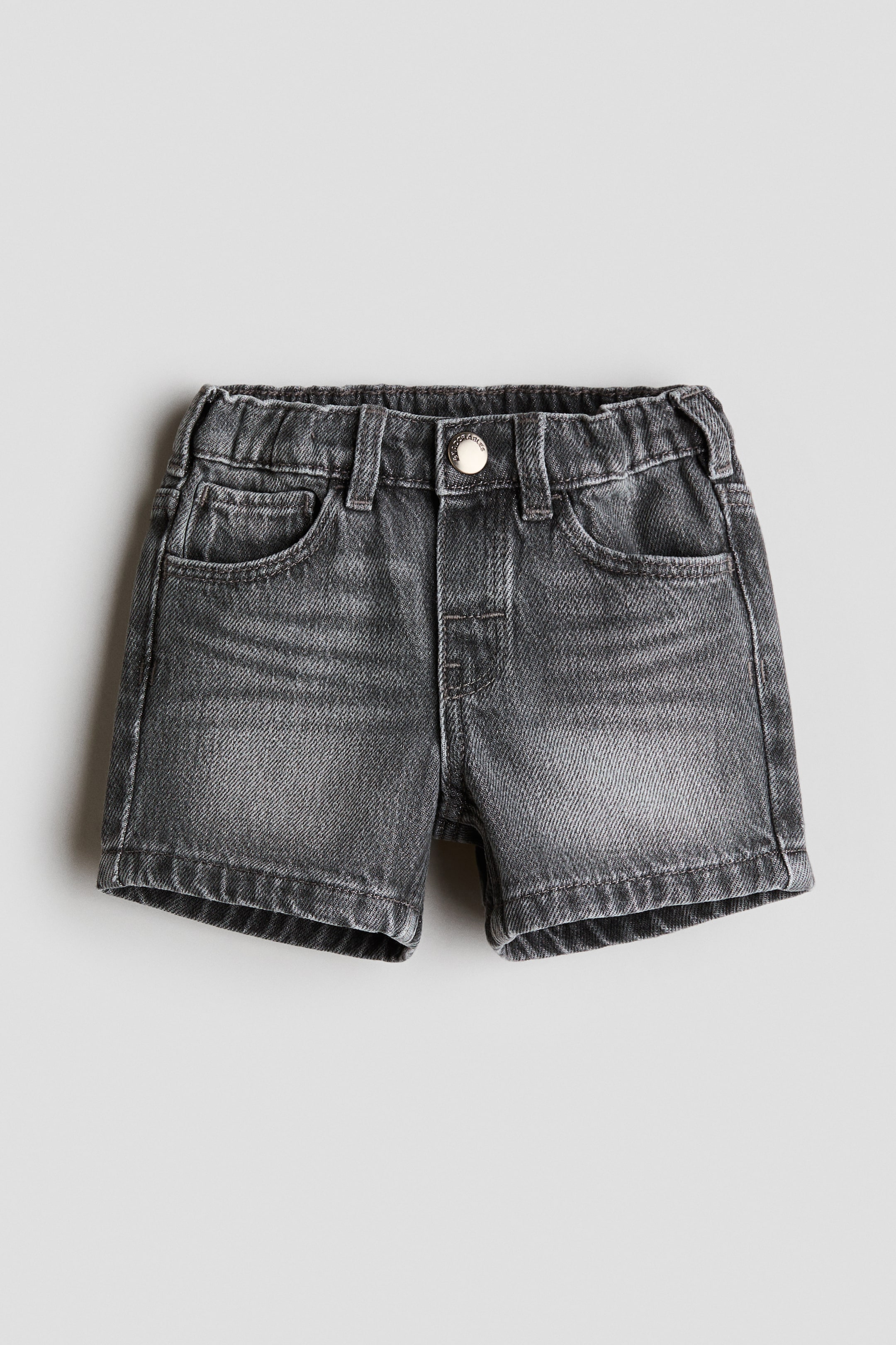 Grotere afbeelding bekijken: H&M Adorables 5-pocket shorts worden van voren getoond, met een gewassen grijze denim stof. Ze zijn ontworpen met een elastische tailleband, riemlussen, een nep gulp en een zilveren drukknoop, samen met twee voorzakken en een muntzakje.
