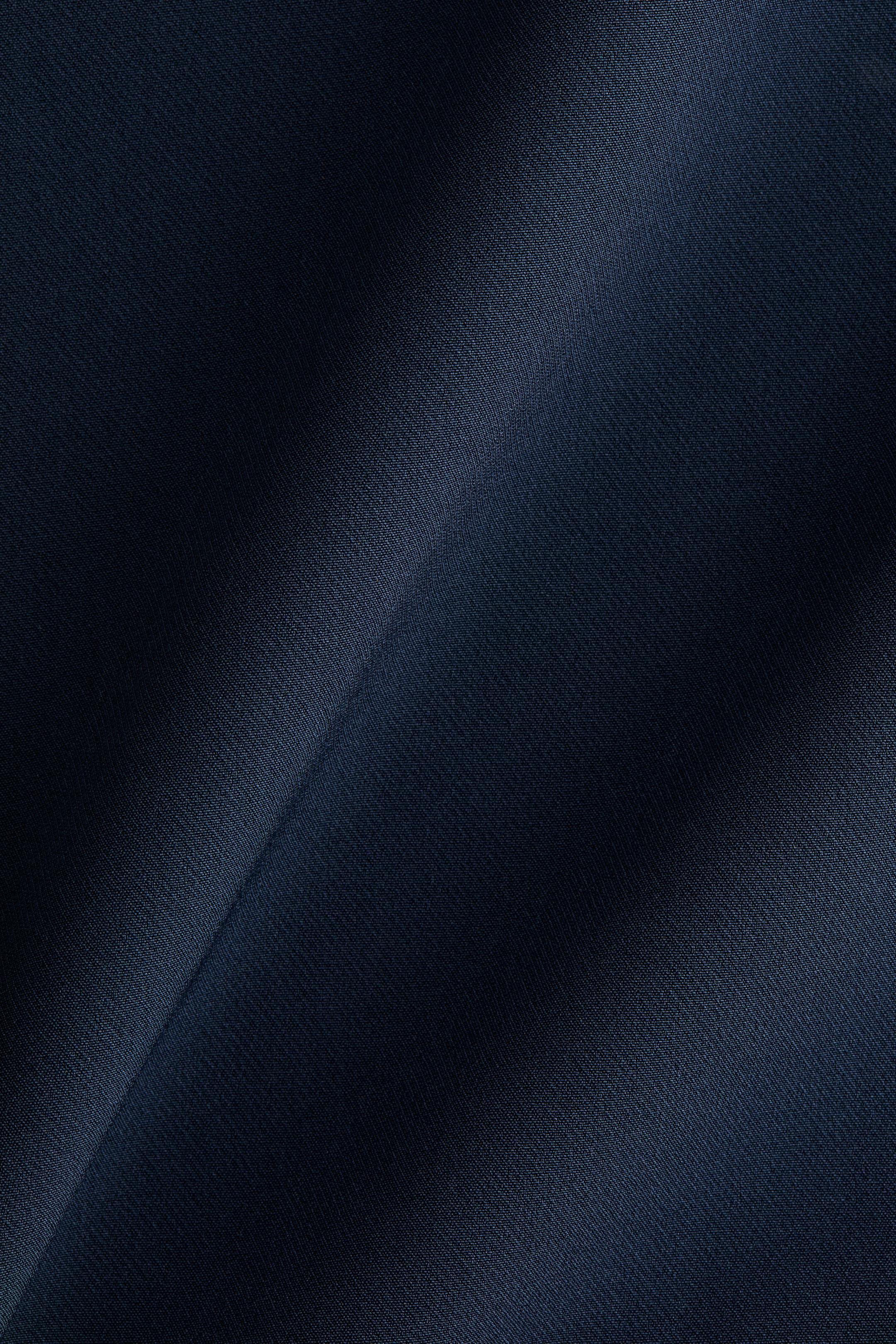 Xem ảnh lớn hơn: Vải màu xanh đậm đang hiển thị một kiểu dệt chéo vân sọc chéo nhẹ nhàng, với những nếp gấp và nếp nhăn nhẹ tạo ra sự biến đổi của ánh sáng và bóng tối trên bề mặt của nó.