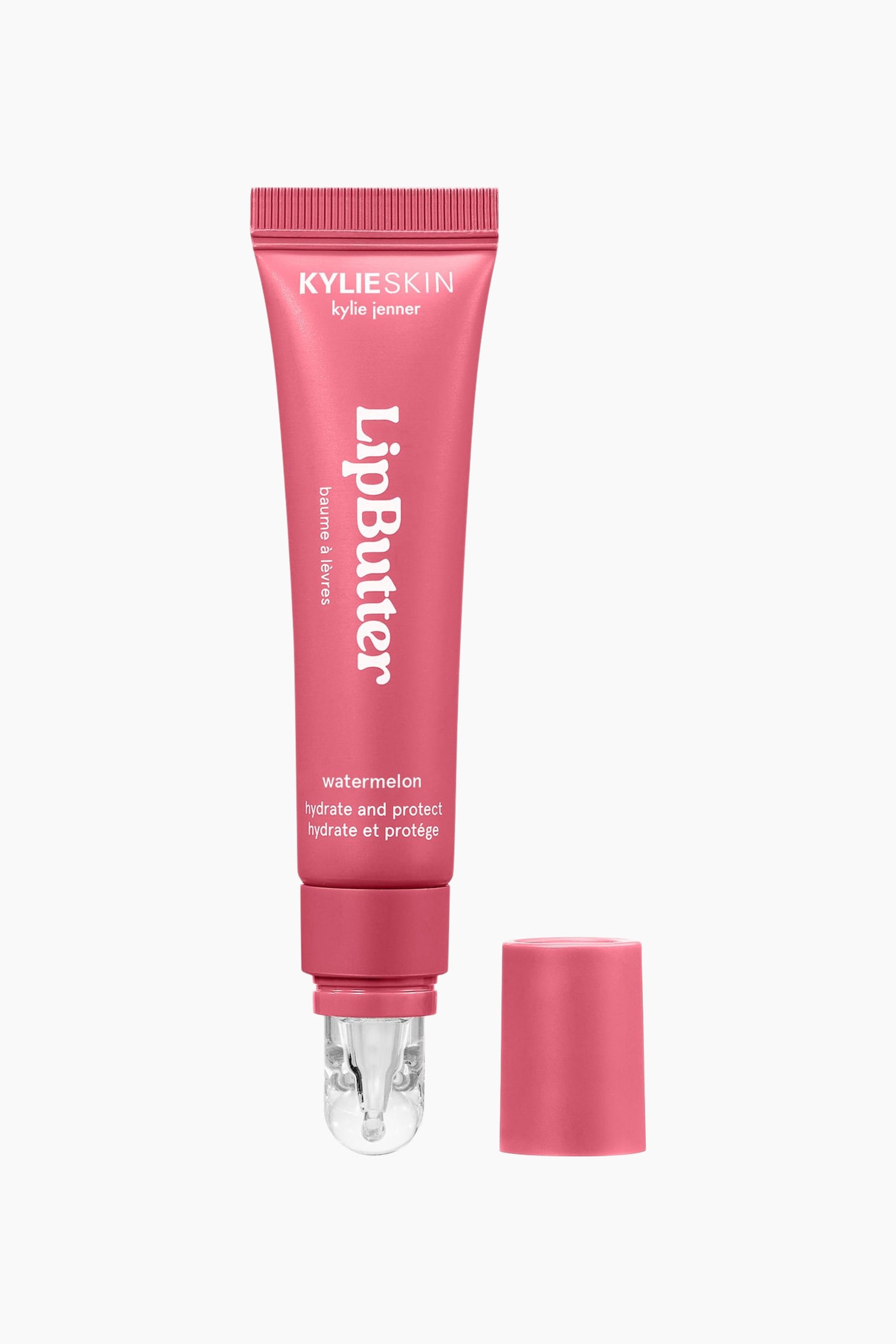 En lyserød squeeze-tube med Kylie Skin Lip Butter står lodret og viser sin gennemsigtige, afrundede applikatorspids nederst, mens det matchende lyserøde låg er taget af og ligger ved siden af. Forsiden af tuben viser hvid branding og produktoplysninger, herunder ordene "Lip Butter" og "watermelon".