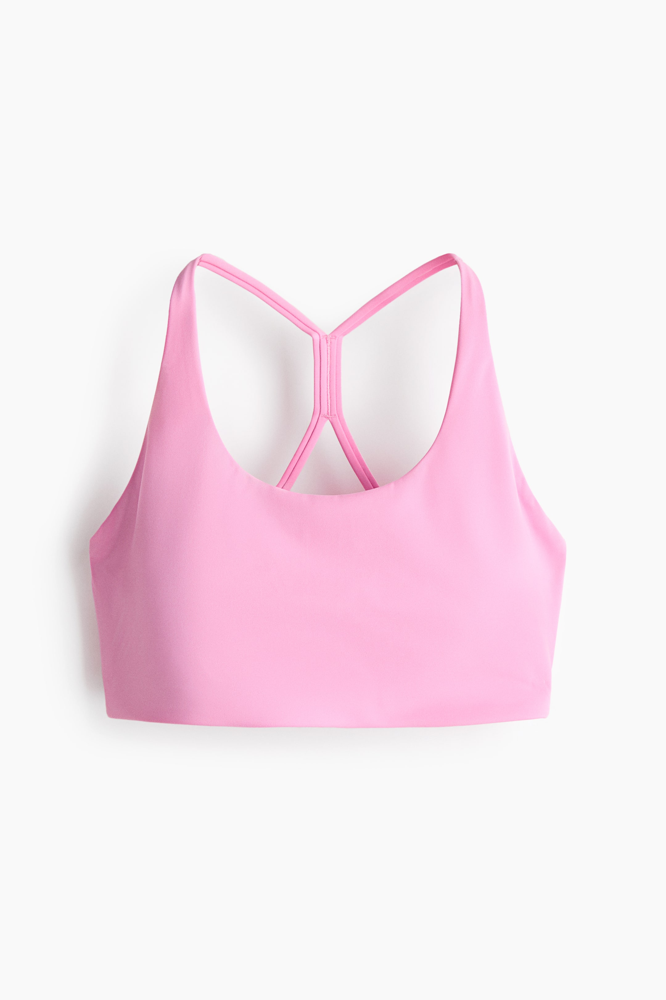 View larger image: A pink sports bra features a scoop neckline at the front and a smooth fabric finish. Thin straps form a racerback design at the back, connecting to a central vertical strap.