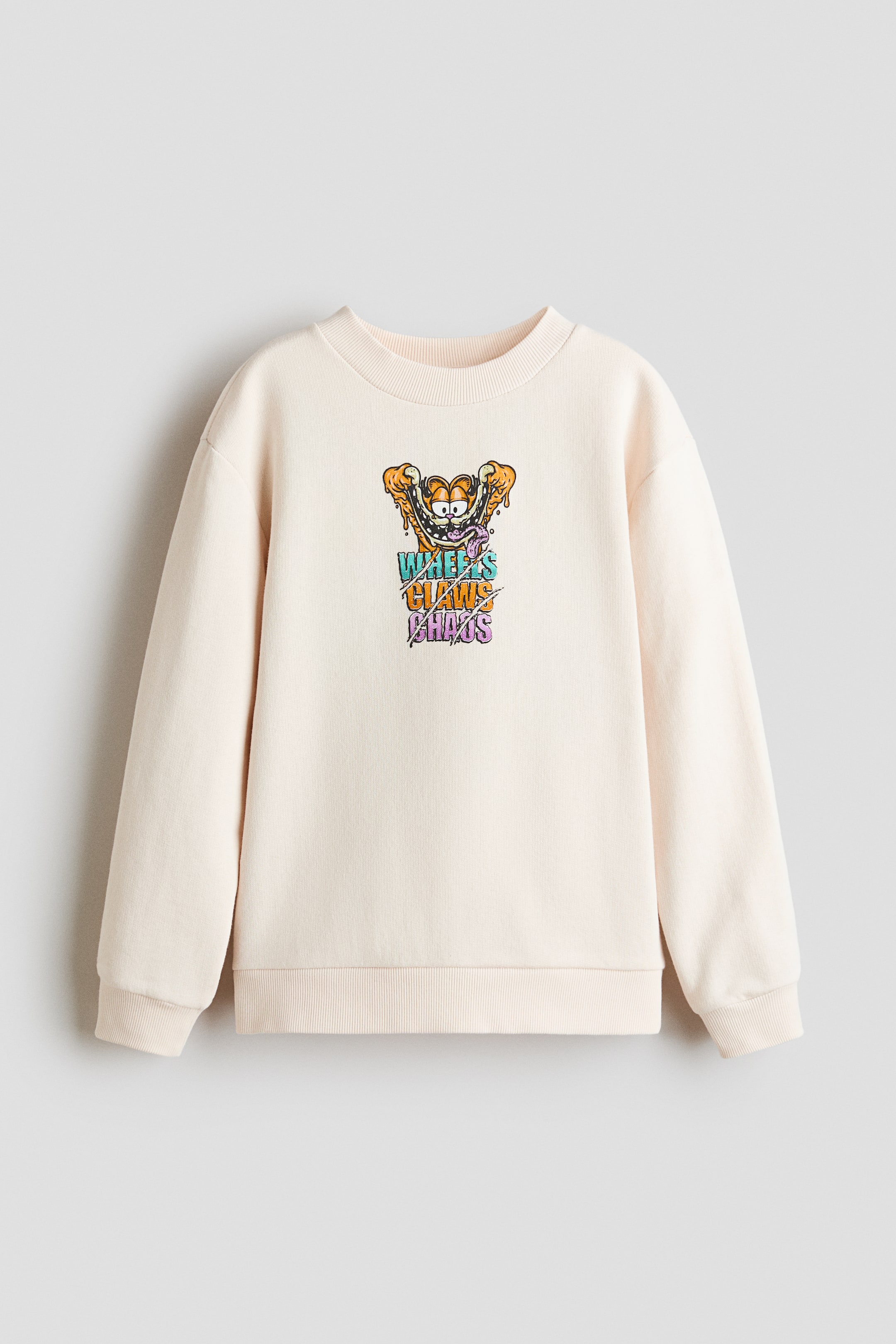 Se større billede: En lys beige sweatshirt med rund hals præsenterer et grafisk print af en tegneserie-kat med ordene 'Wheels Claws Chaos' på forsiden. Den har lange ærmer, ribbede manchetter og en ribbet kant.