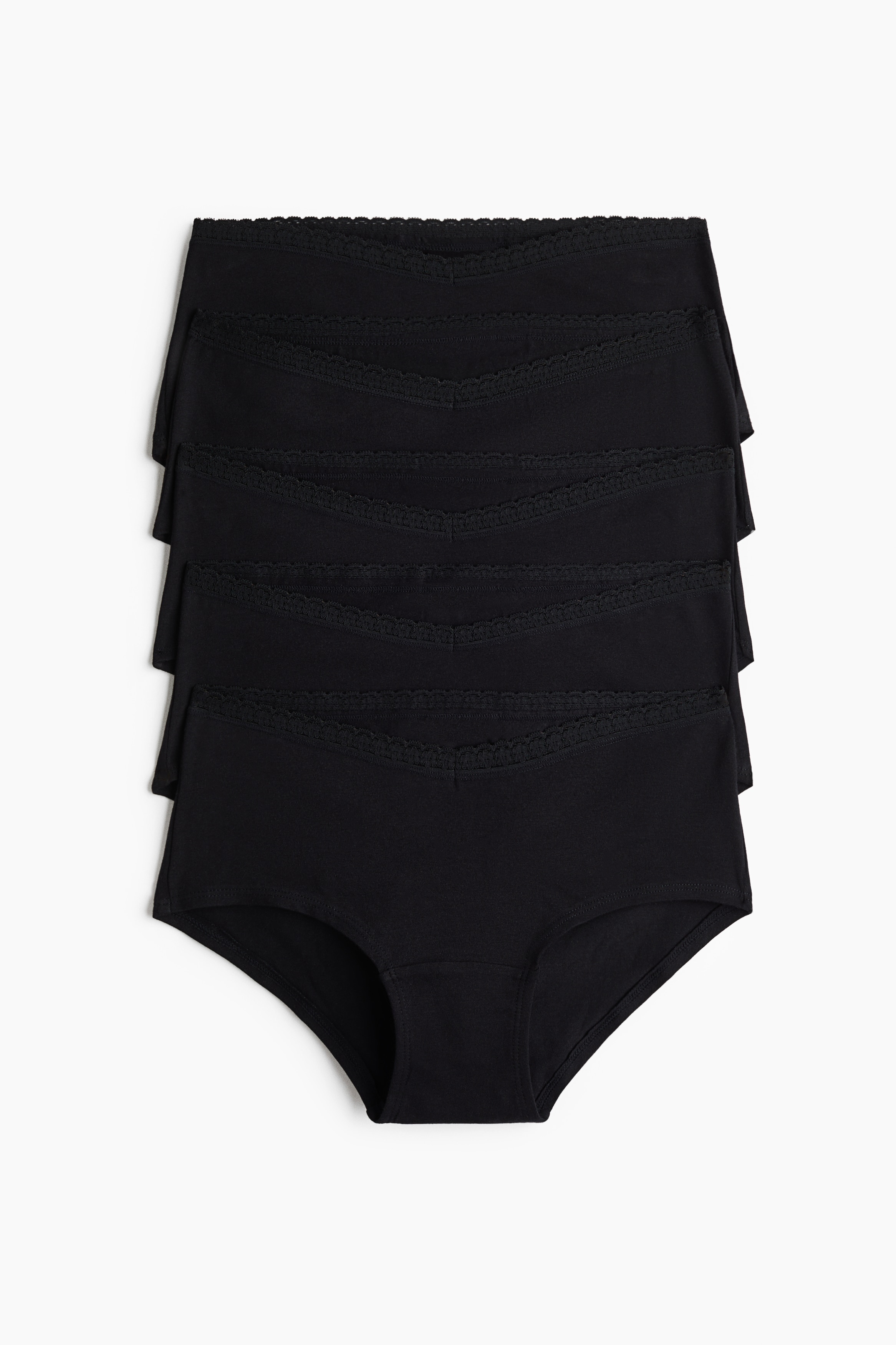 Un soutien-gorge noir sans armatures avec une bordure en dentelle délicate le long des bonnets et sur le centre-gorge est présenté de face, légèrement incliné vers la droite. Il est assorti à une culotte noire côtelée qui repose bas sur les hanches.