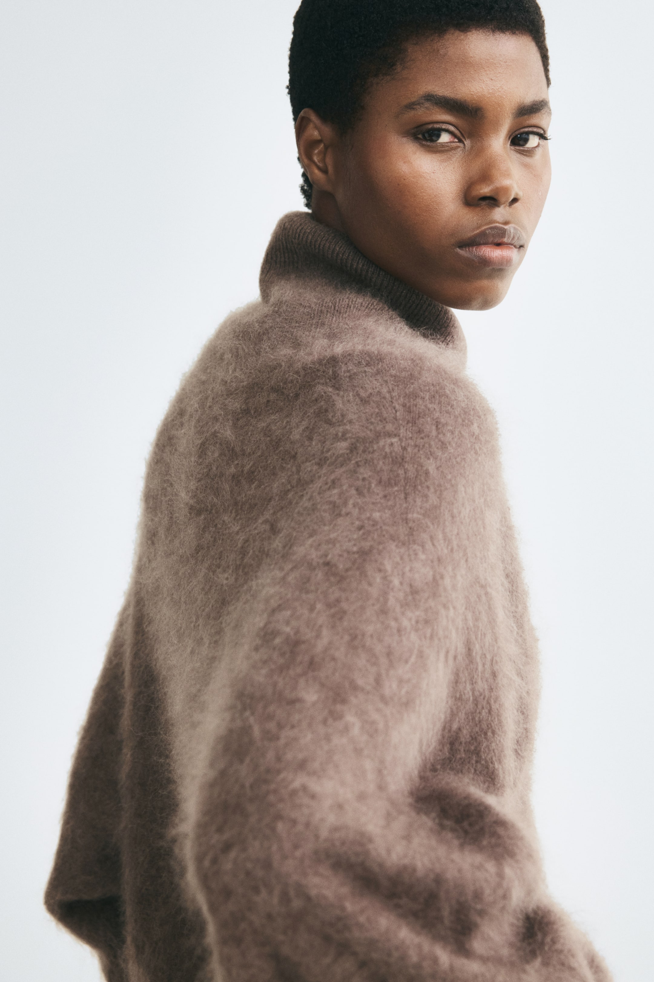 View larger image: The model is wearing an oversized sweater made from brown brushed wool knit with a high ribbed neck.